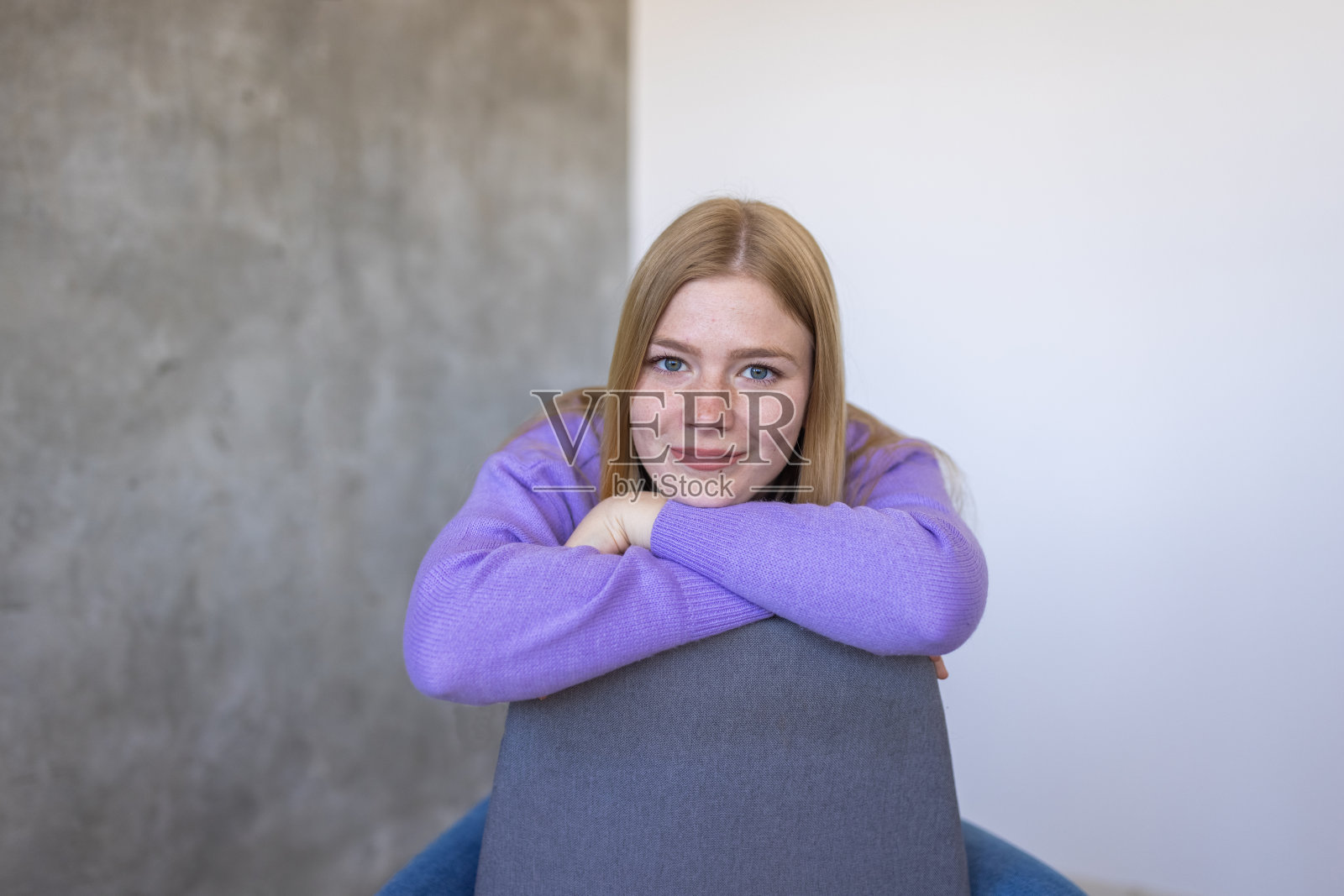 白人妇女坐在椅子上,穿着紫色毛衣照片摄影图片