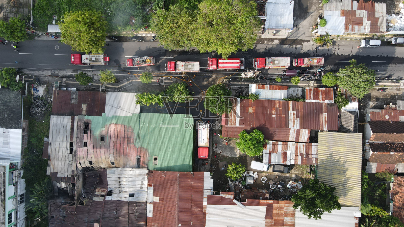 消防队员扑灭燃烧的家具厂建筑废墟的鸟瞰图,屋顶倒塌,浓烟滚滚。照片摄影图片