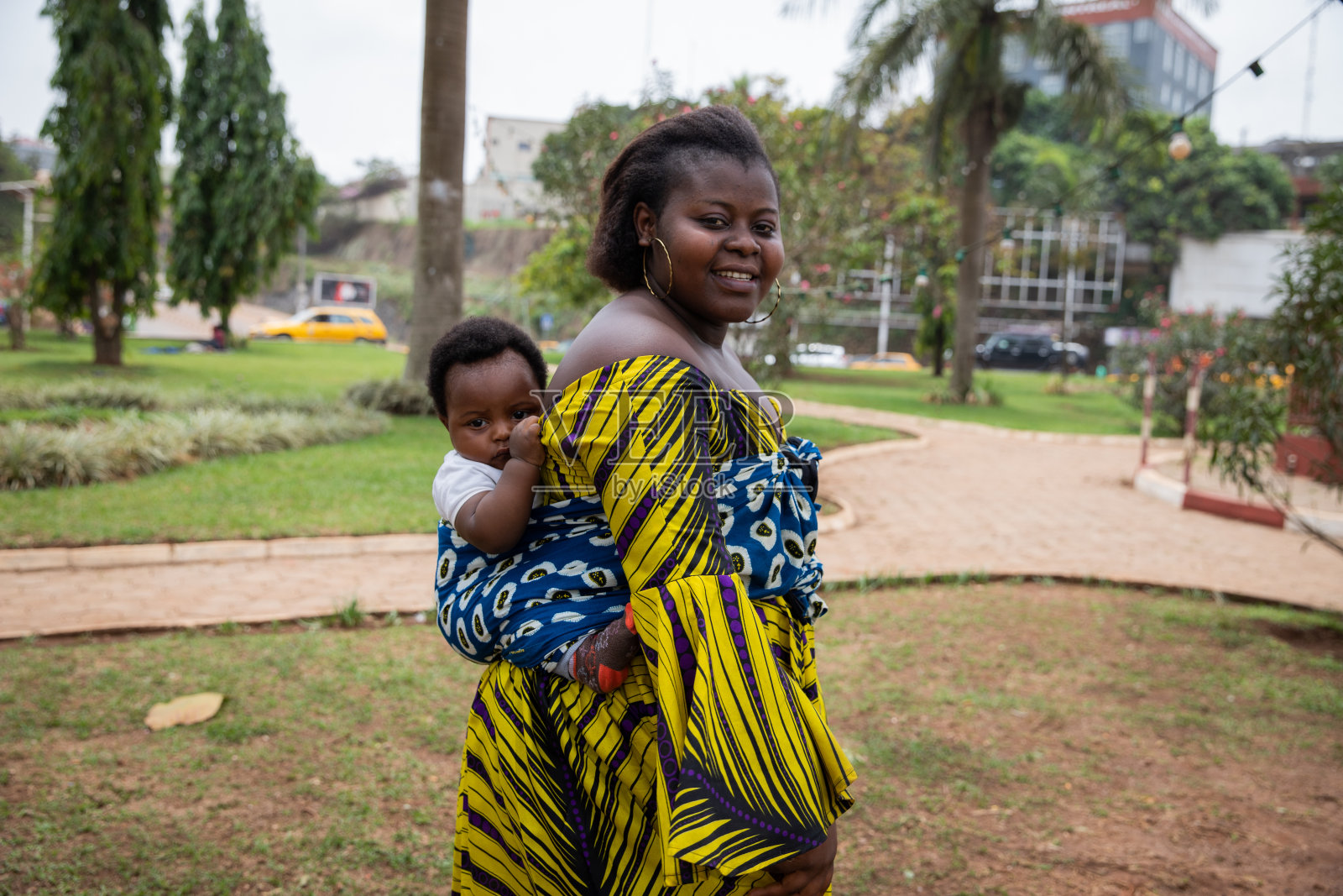 一位非洲母亲用头巾抱着绑在她背上的儿子的肖像照片摄影图片