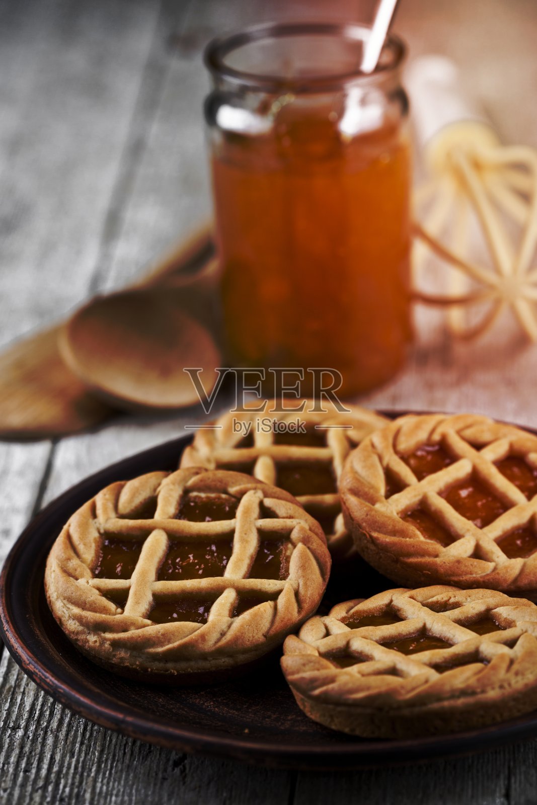 新鲜出炉的果酱或杏酱馅饼,放在陶瓷盘和厨房烘焙用具上。照片摄影图片