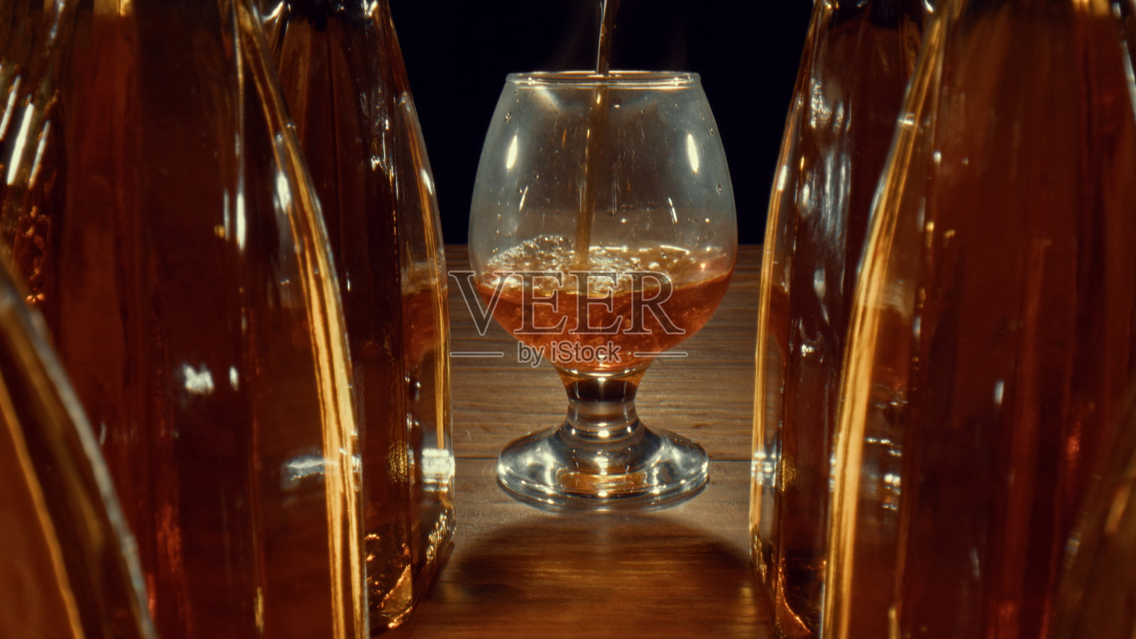 饮料正倒在干邑和威士忌旁边的玻璃杯里照片摄影图片