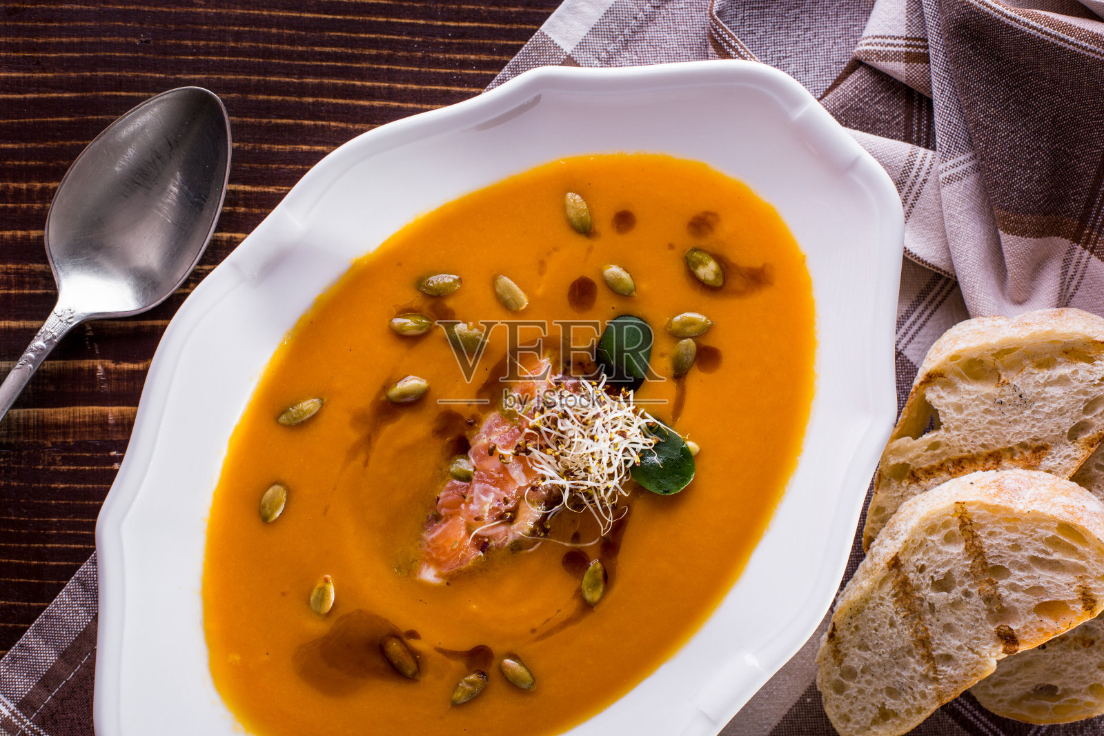 三文鱼汤,嫩苗,绿豆沙拉,用勺子盛在盘子里,还有炸面包照片摄影图片