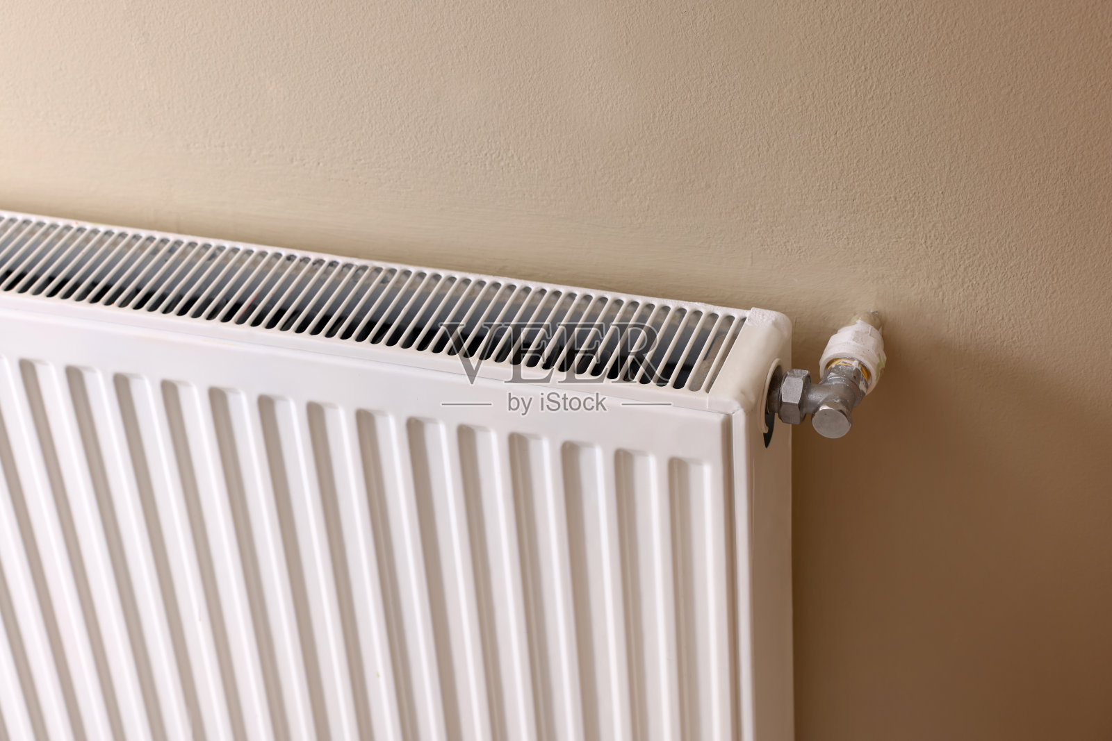 米色墙上的现代散热器。集中供暖系统照片摄影图片
