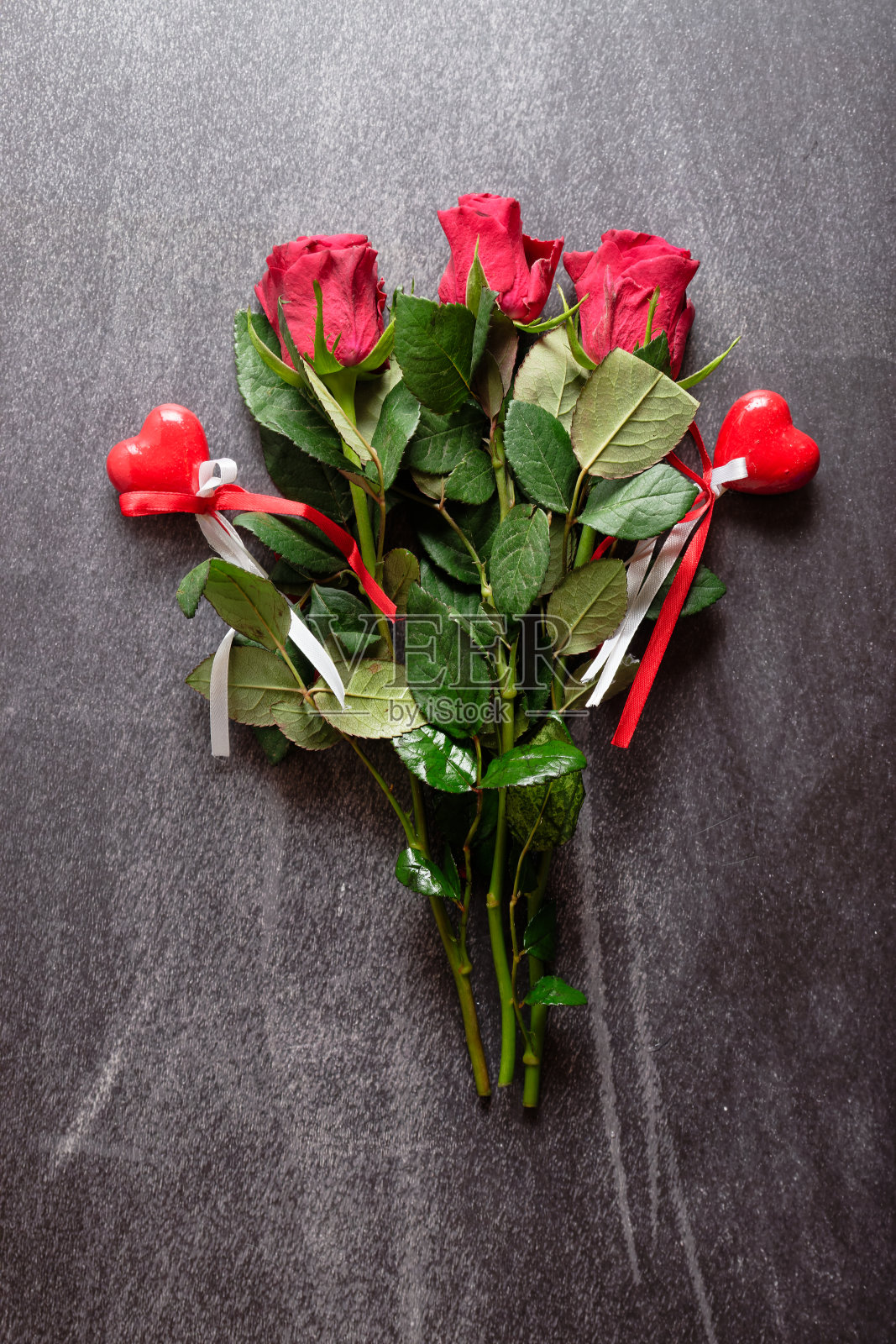 灰色混凝土表面上的红玫瑰。情人节背景。照片摄影图片
