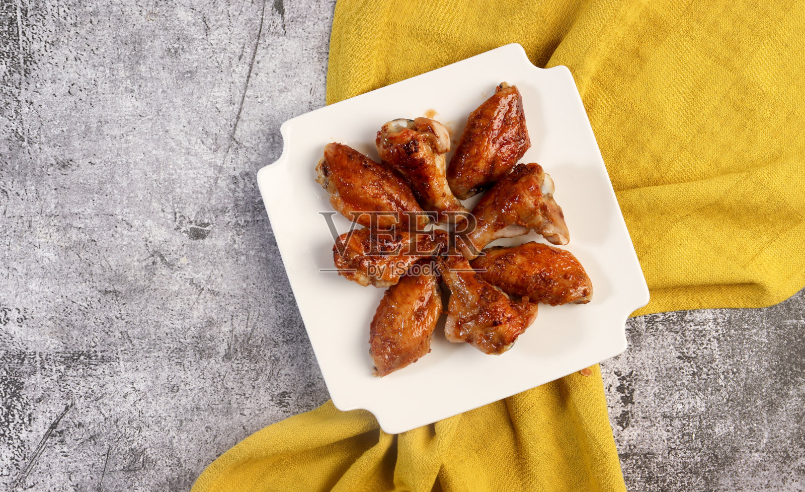 蜜汁鸡翅放在深灰色背景的白色方盘上。俯视图,平面布局照片摄影图片