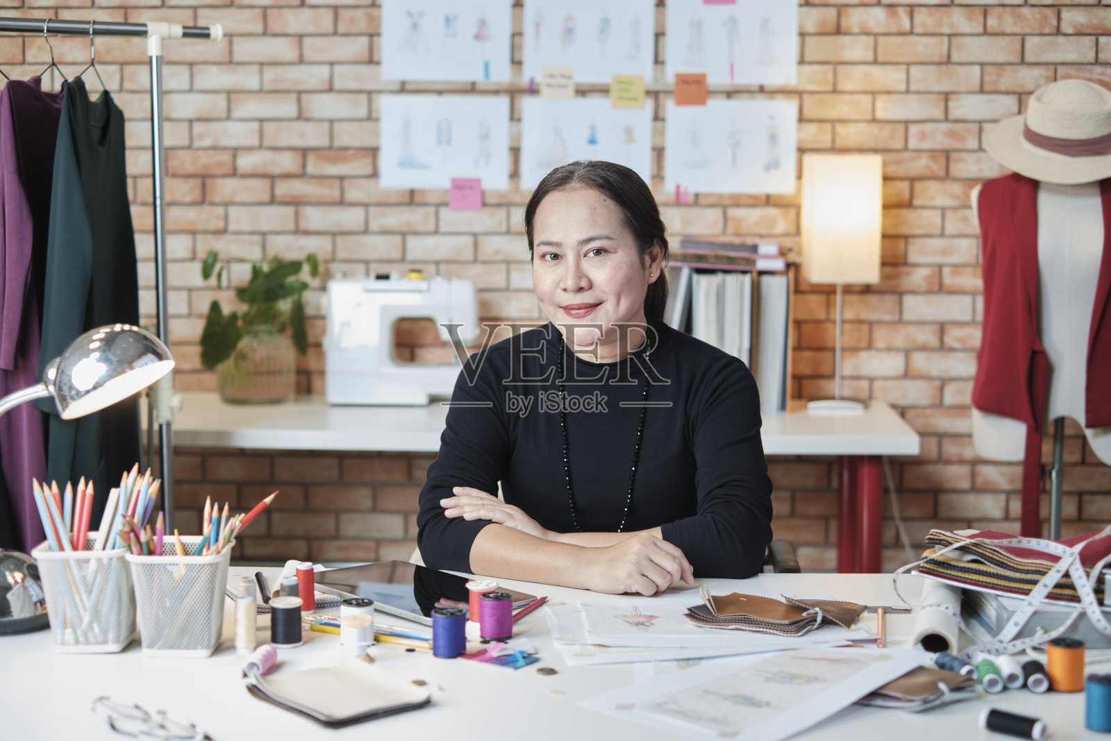 在造型师工作室的专业亚洲时装设计师和裁缝的肖像。照片摄影图片