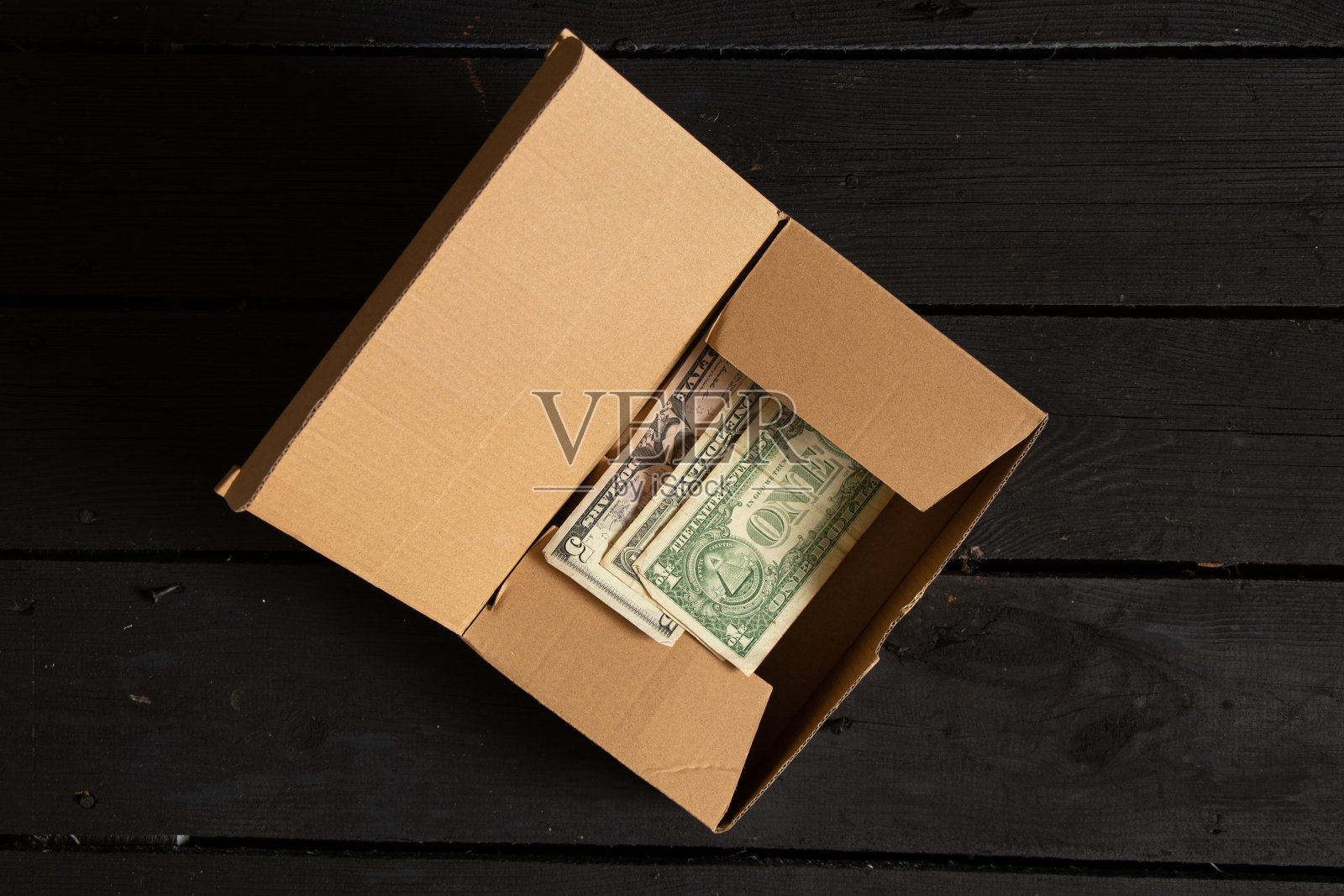 美元放在黑色木桌上的一个棕色的盒子里,钱放在一个盒子里照片摄影图片