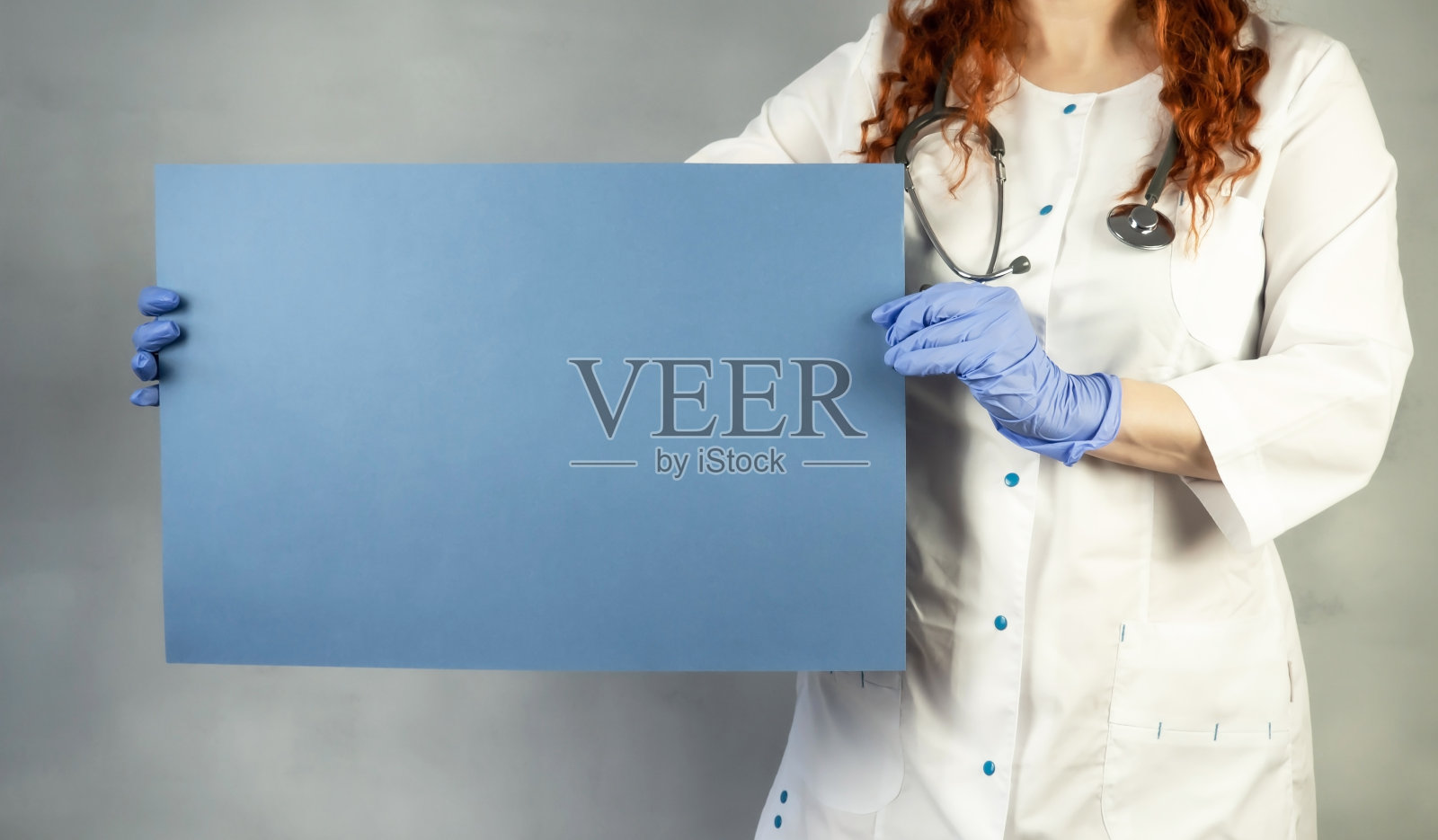 医生拿着一张蓝色的纸。医生的手戴着防护手套,上面有海报。布局。海报。横幅。警告。发短信的地方。照片摄影图片