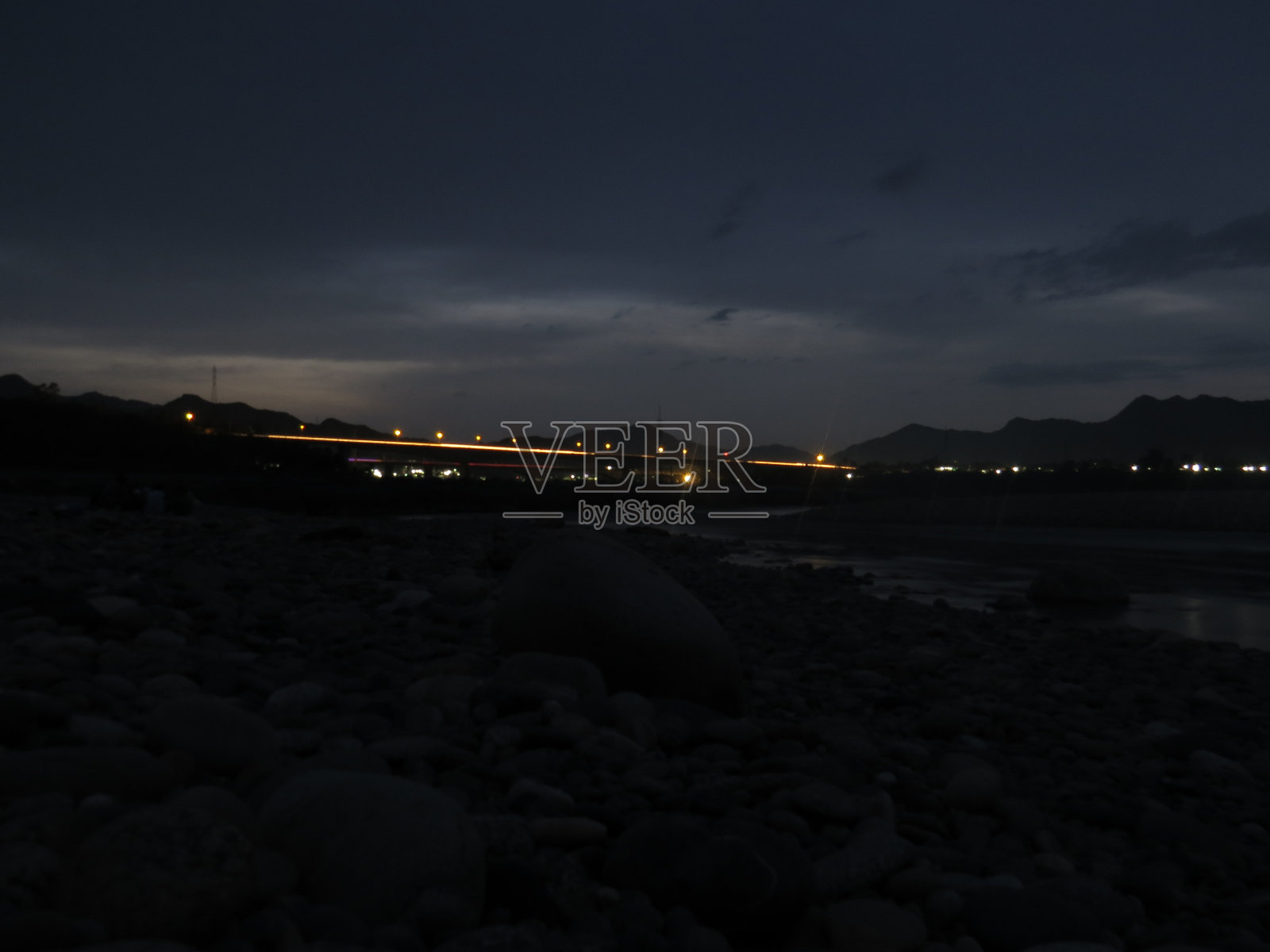 夜间摄影。地平线。自然风景。山与山之间的河流。夜间的人工照明。照片摄影图片