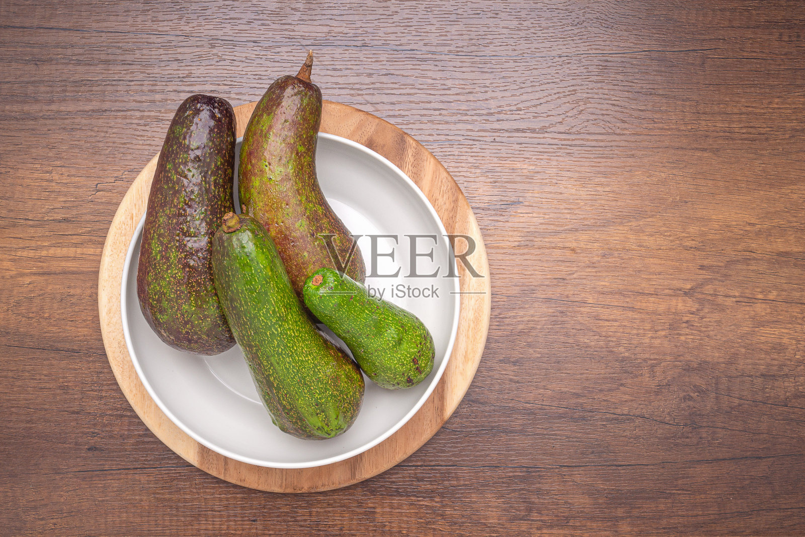 牛油果放在白色的盘子里,木箱放在木桌上。照片摄影图片