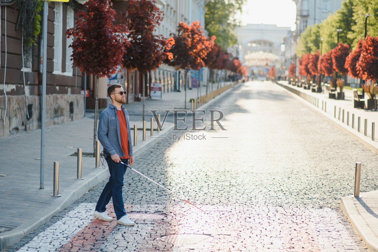 盲人拿着白手杖在城市里过马路,特写照片摄影图片
