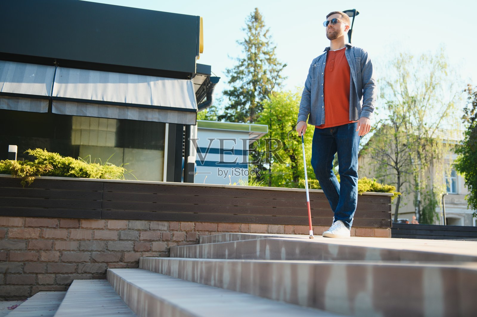 盲人拄着拐杖走在人行道上照片摄影图片