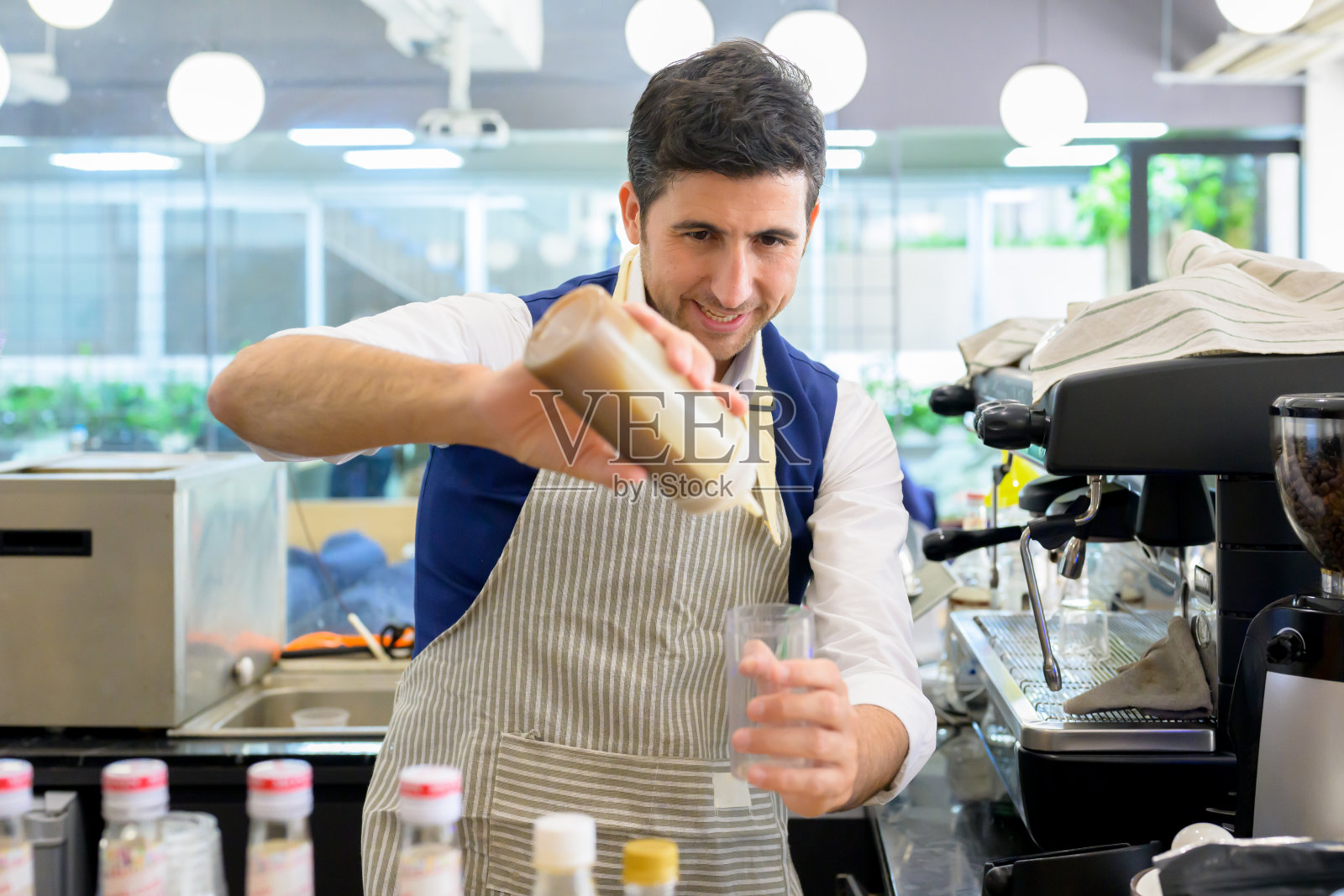 微笑的肖像男性咖啡师在咖啡店,帅哥在咖啡站工作照片摄影图片