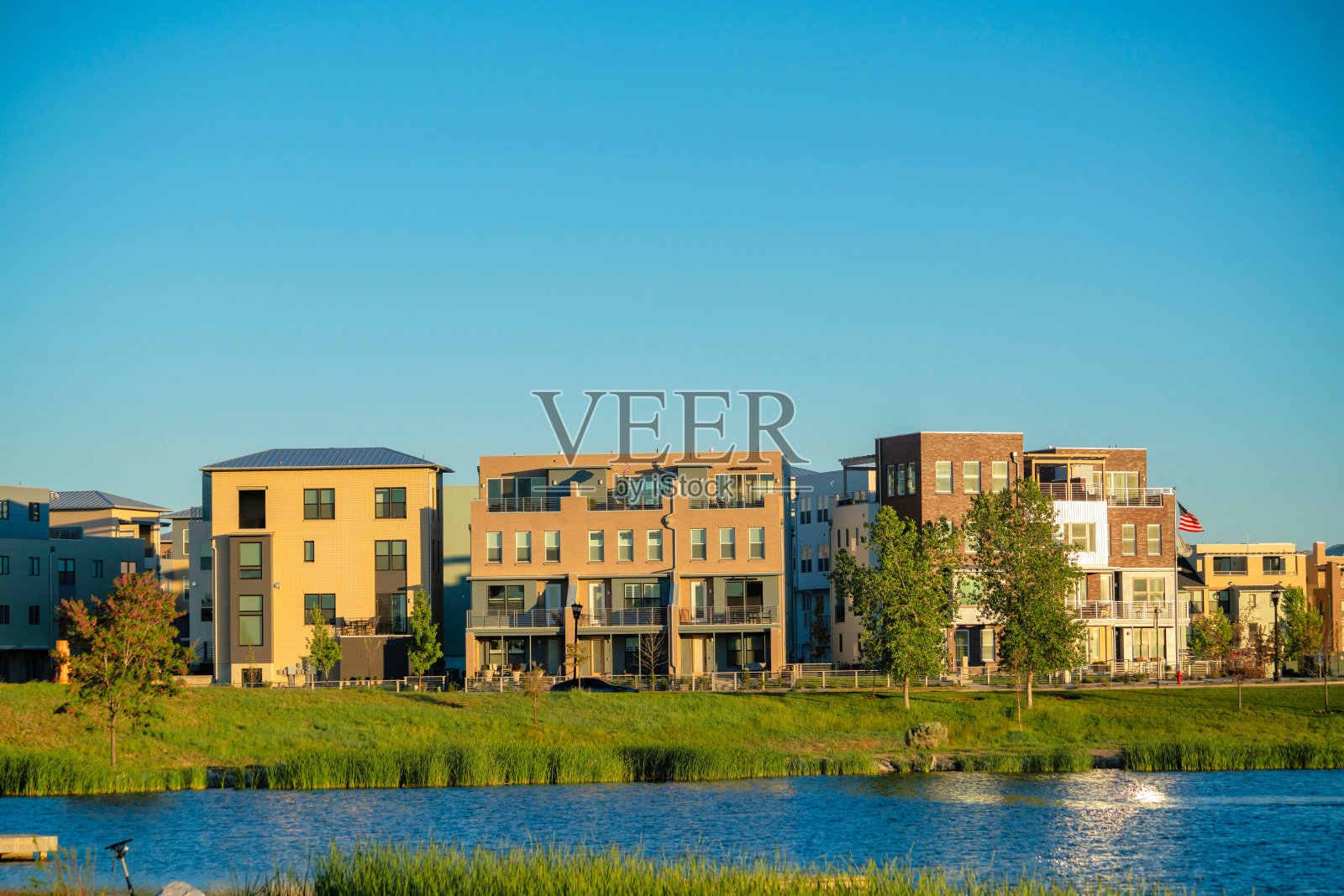 绿树成荫的建筑与草地相映成趣,在干净的天空下照片摄影图片