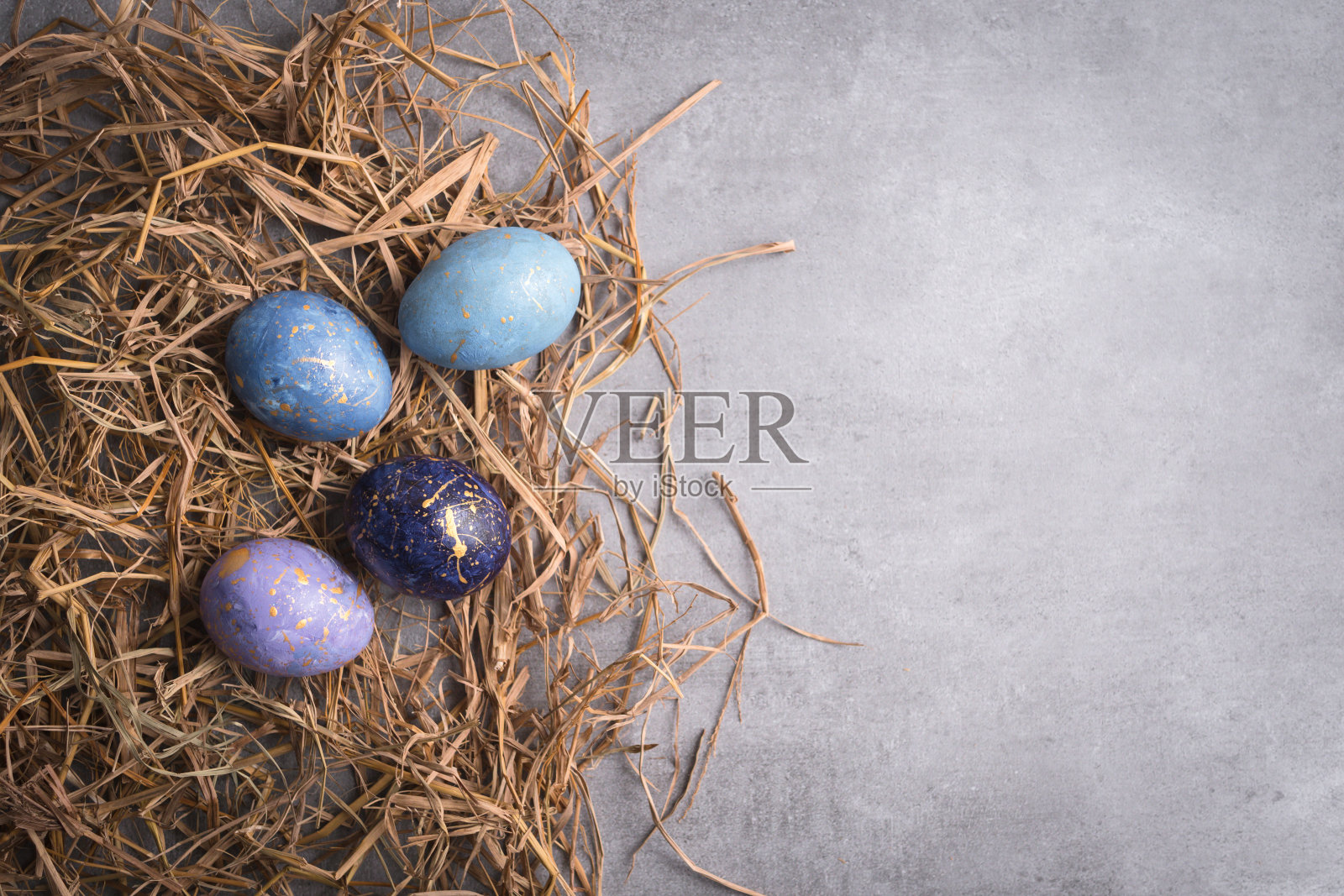 颜色充分复活节彩蛋和稻草窝在灰色背景。照片摄影图片