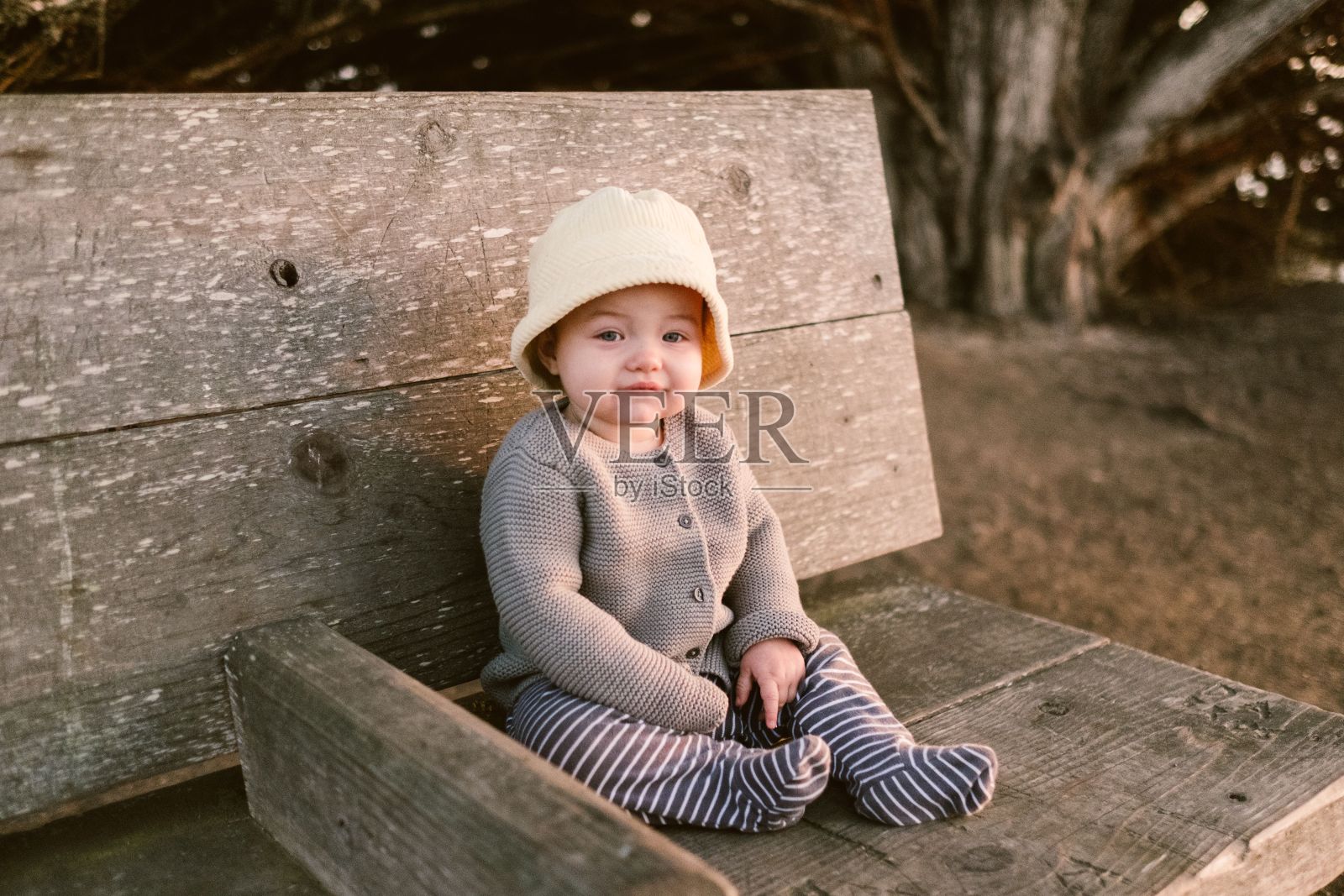 可爱的女婴坐在木凳上,戴着一顶黄色的帽子,美国照片摄影图片