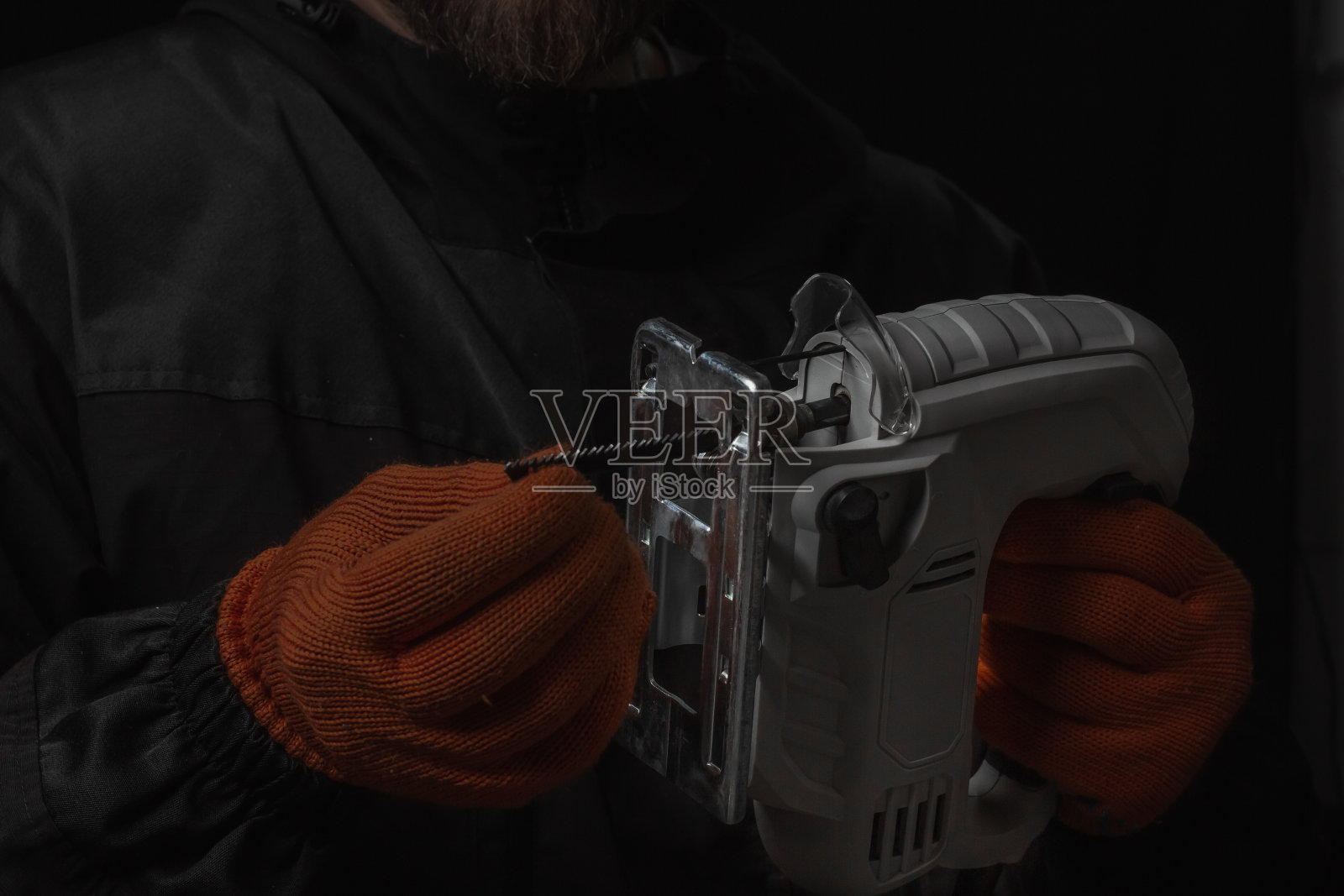 电动拼图,在妈妈的手锯木材隔离在黑色背景照片摄影图片