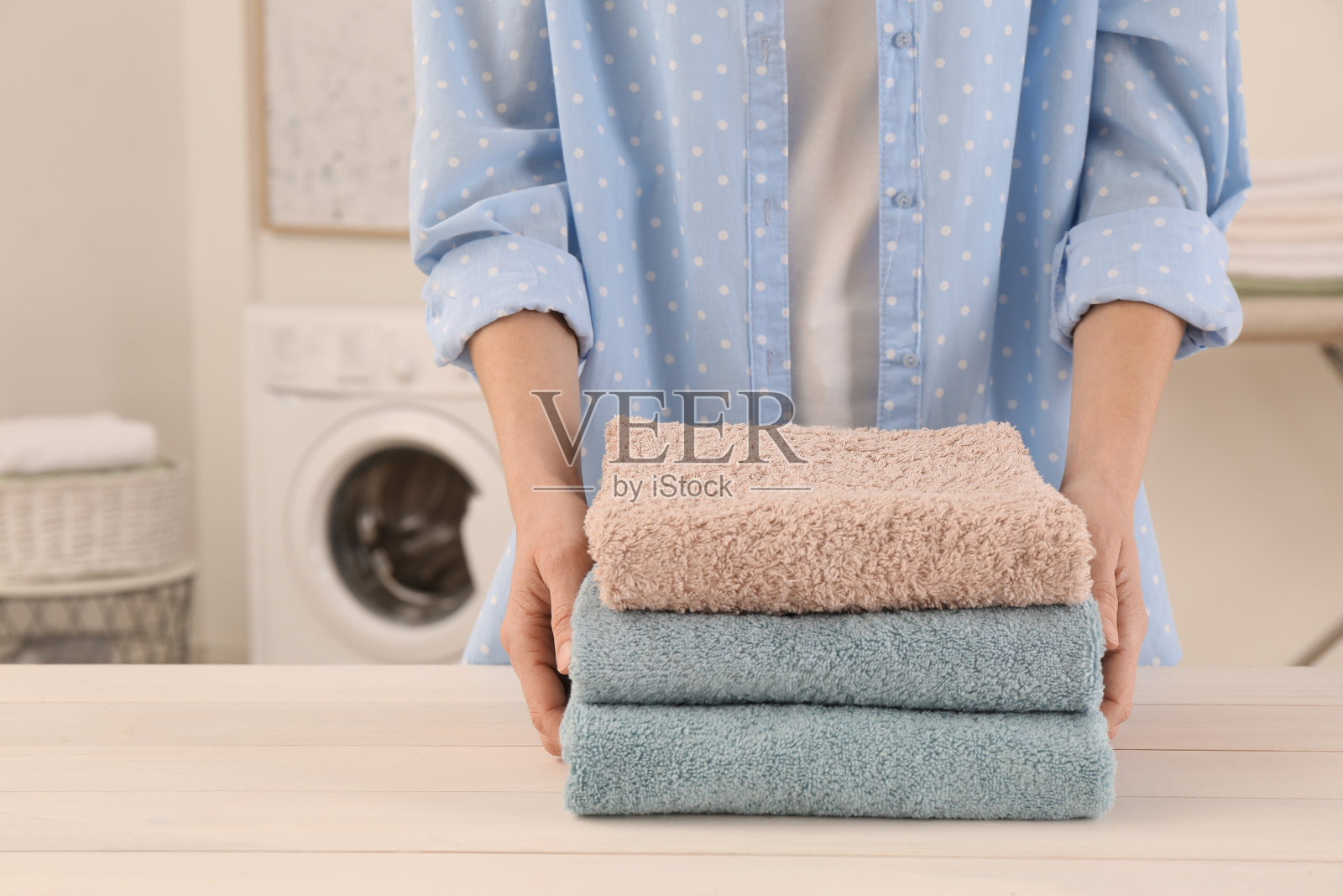 女子与折叠干净的毛巾布在桌子在洗衣房,特写照片摄影图片