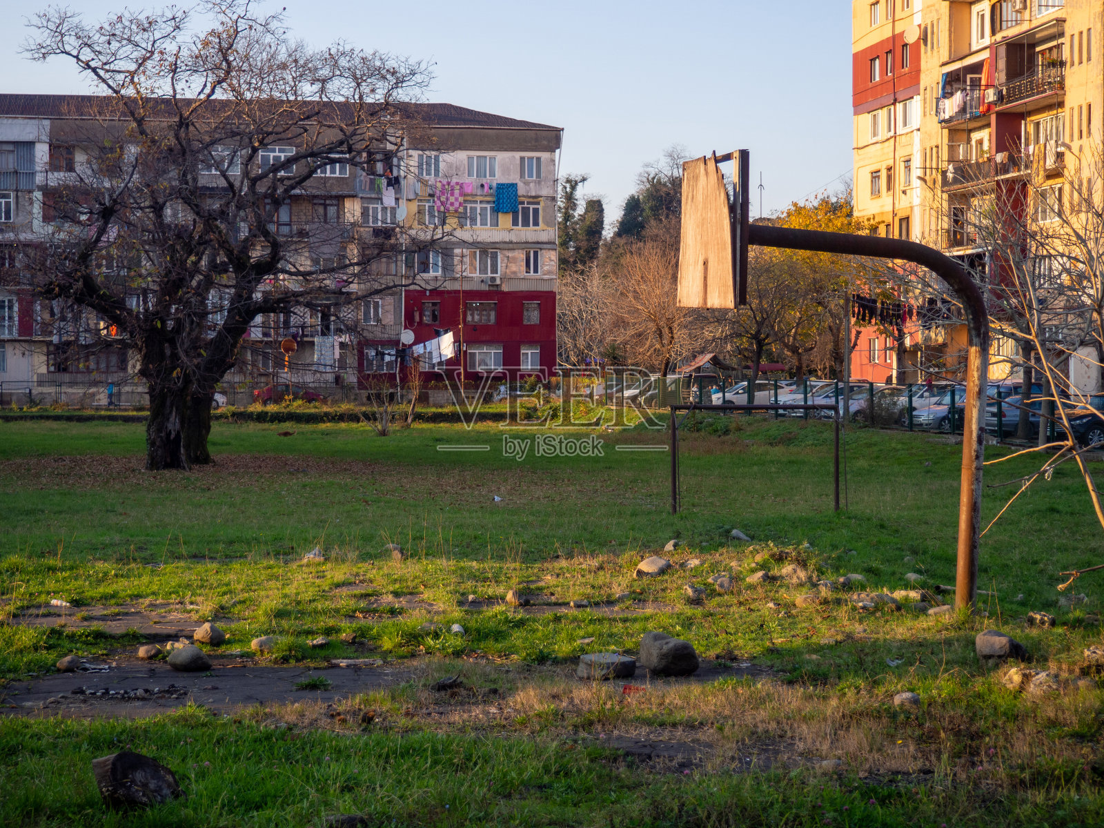 废弃的篮球场。一个没有戒指的旧篮球篮板。在院子里玩游戏。照片摄影图片