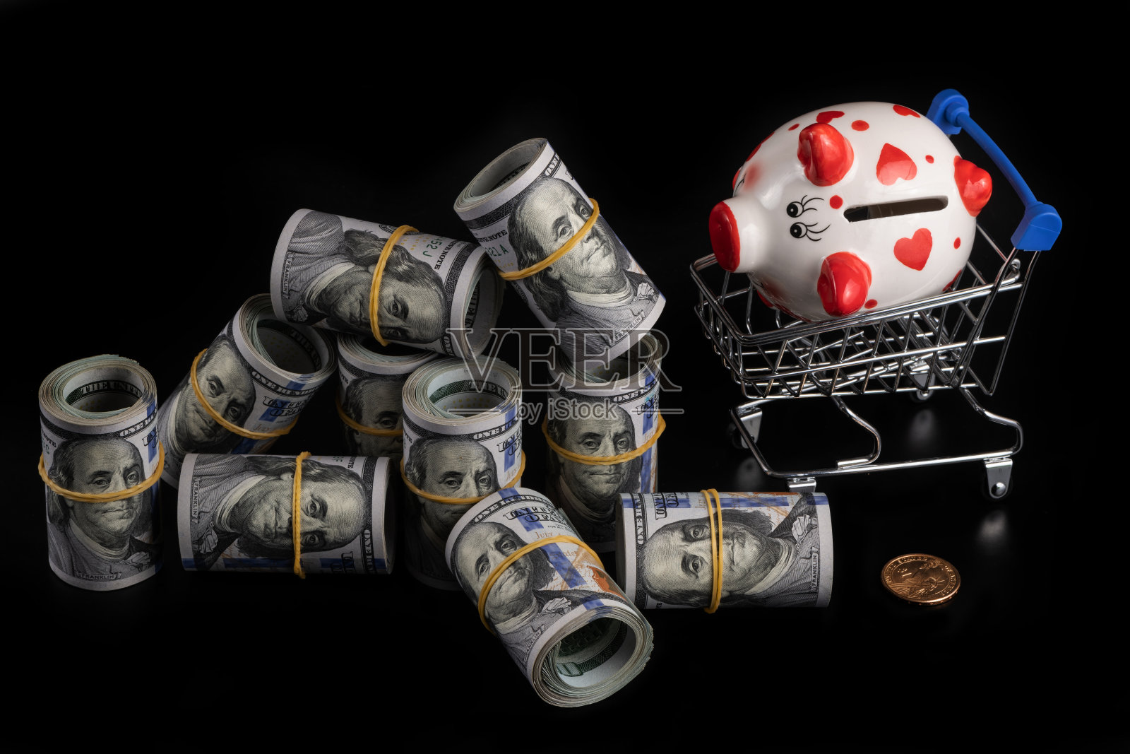 超市里的迷你购物车里有一个存钱罐,黑色背景上有一包美元照片摄影图片