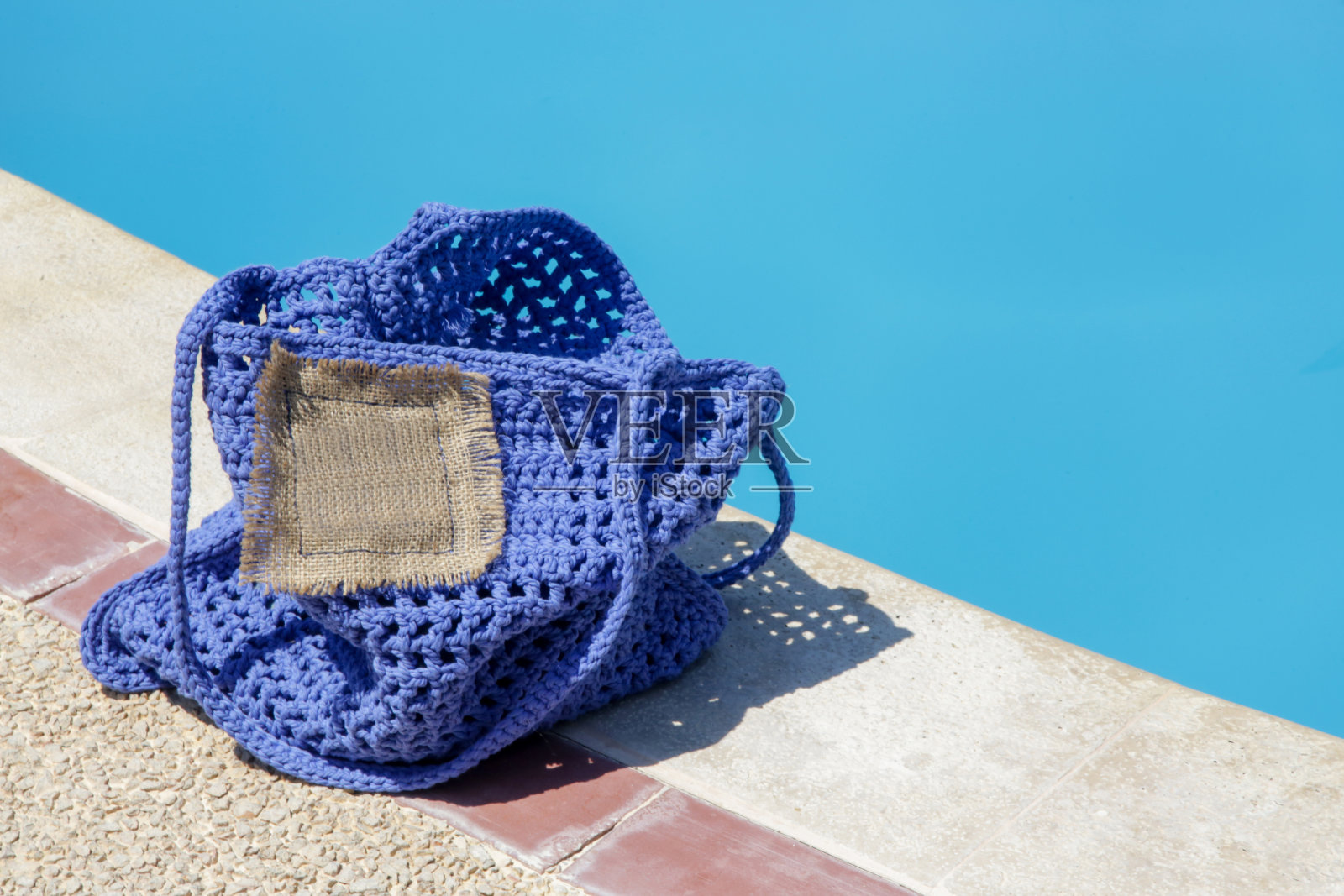 亮蓝色手工钩针手提包在泳池边照片摄影图片