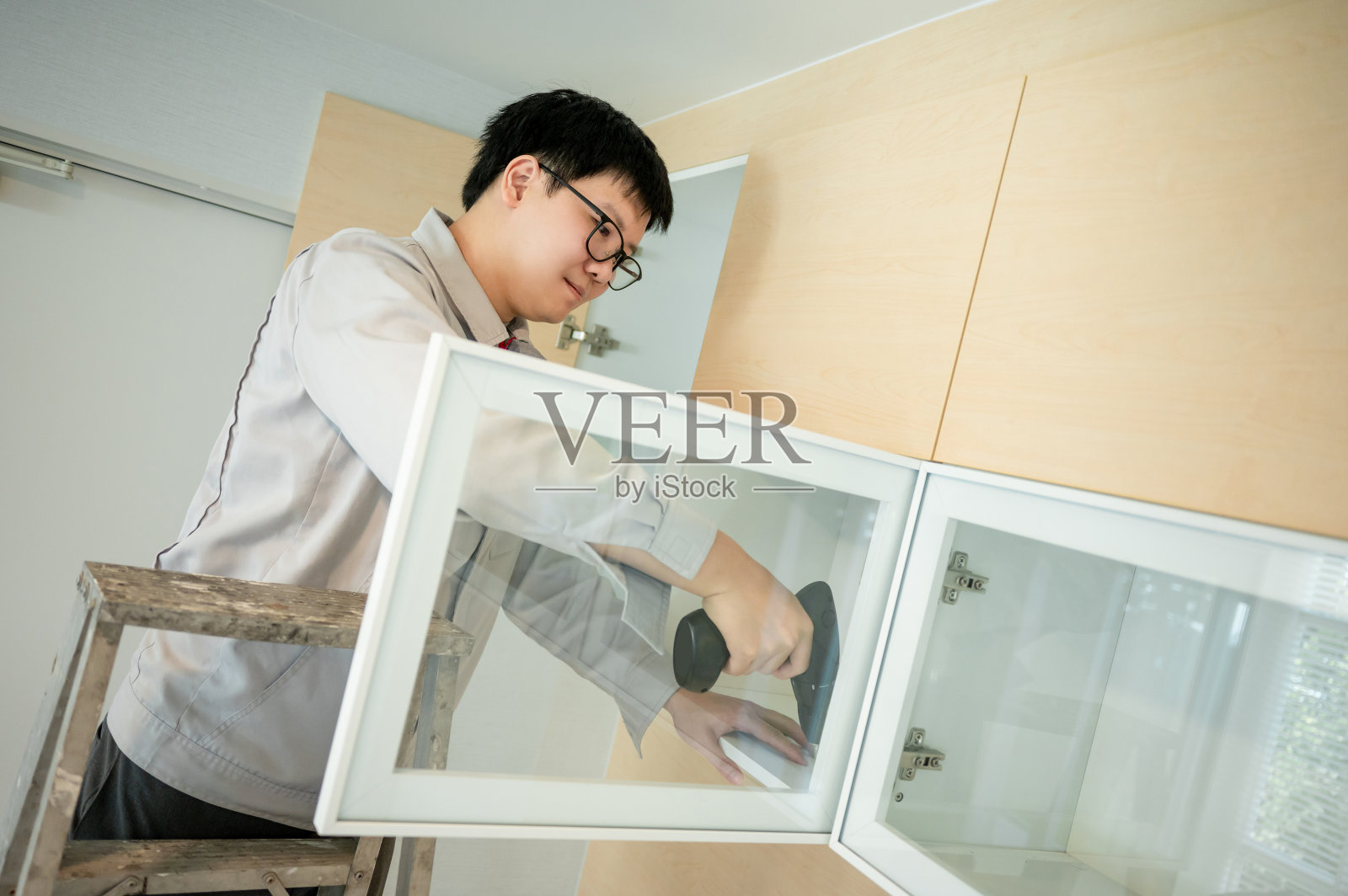 亚洲男性家具装配工使用电钻螺丝刀照片摄影图片