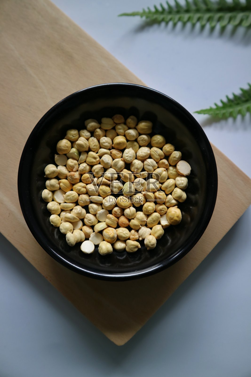 卡康阿拉伯或鹰嘴豆在黑色圆形盘和木制切板和白色背景。鹰嘴豆是营养丰富的食物。健康天然的素食。照片摄影图片