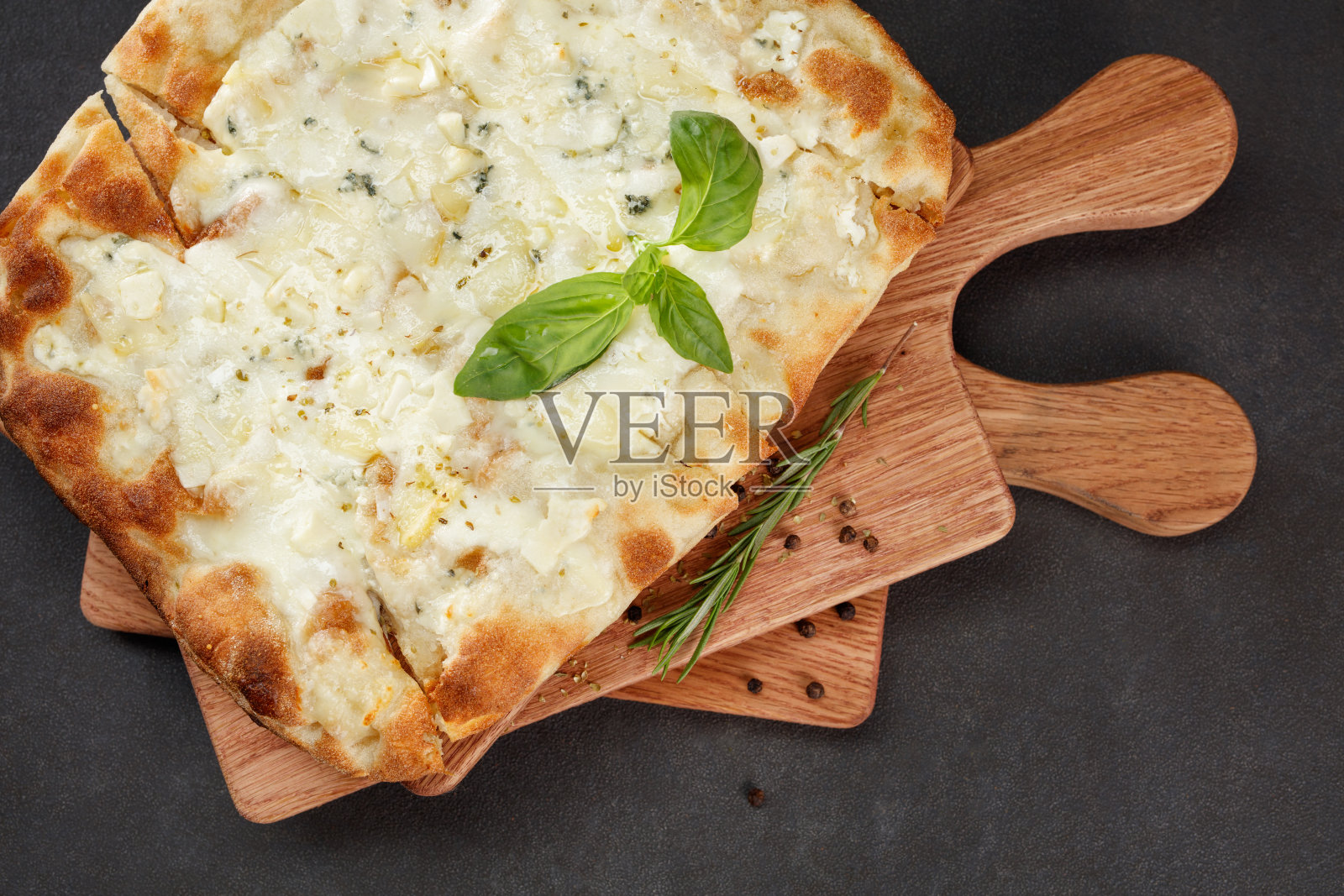 脆皮四芝士披萨,木板上放罗勒。俯视图照片摄影图片