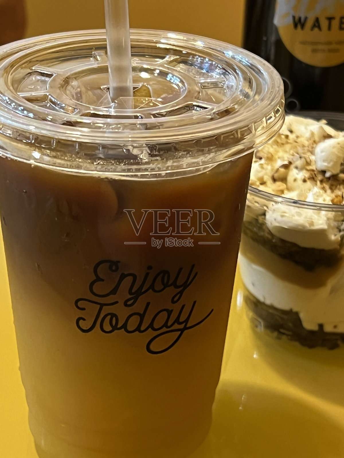 外带带吸管的塑料杯饮料。冰橙咖啡和巧克力可可饮料在户外咖啡馆与瀑布为背景。自然的咖啡馆照片摄影图片