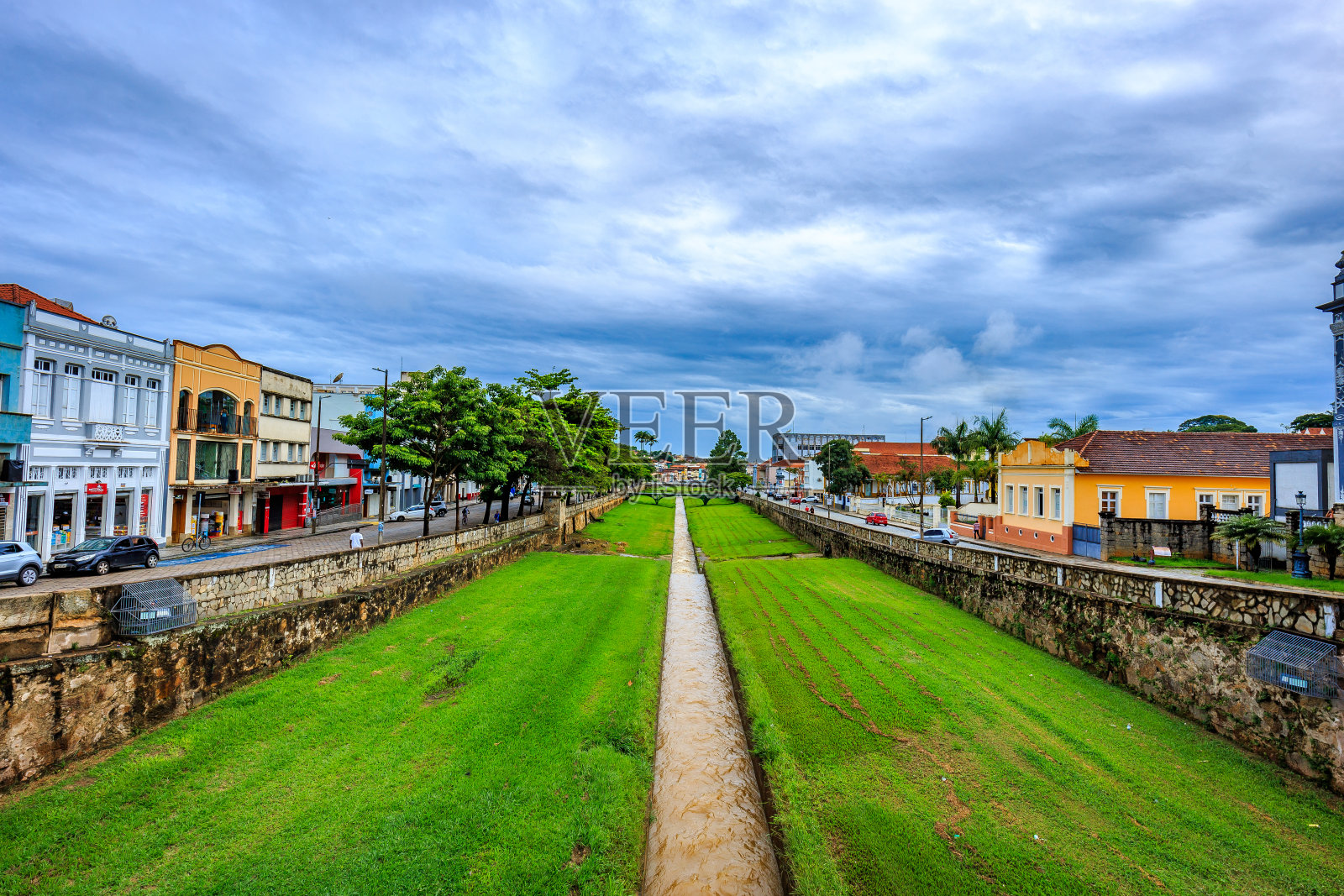 巴西米纳斯吉拉斯州的Sao Joao del Rei。在阴天穿过城市的河流和老建筑。照片摄影图片