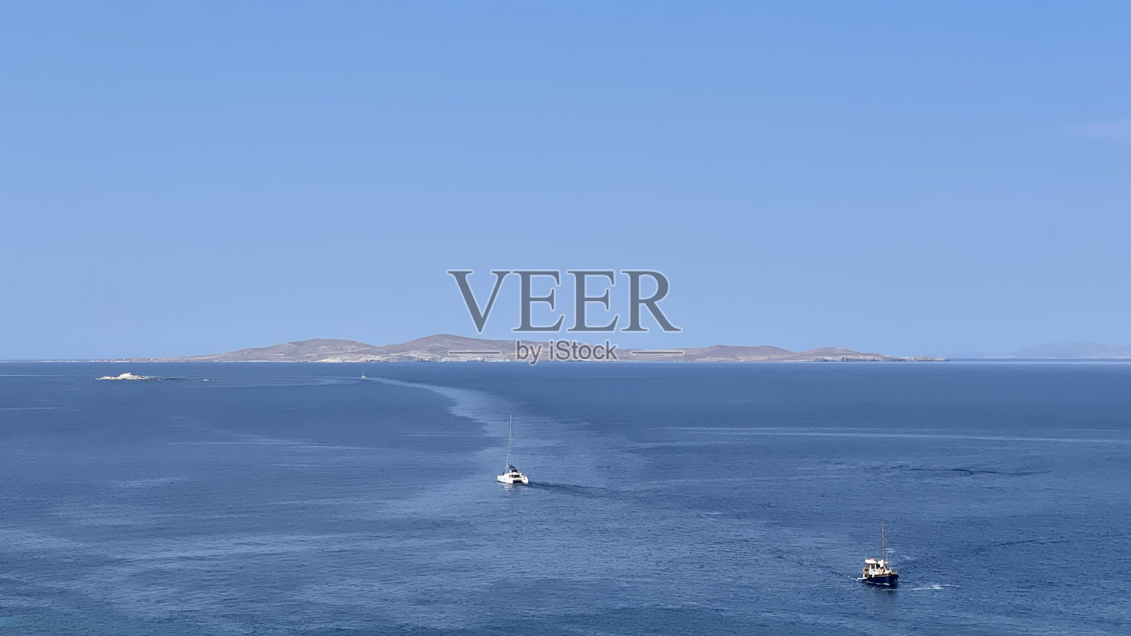 船在蓝色平静的大海上航行,背景是山和天空照片摄影图片