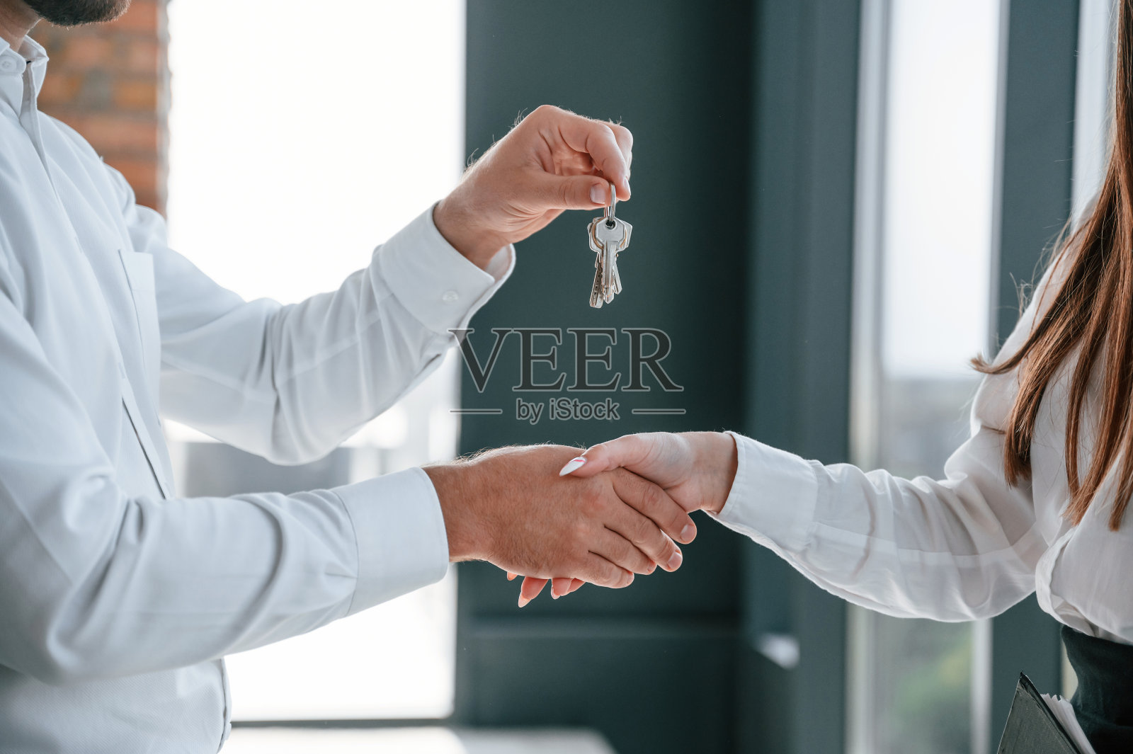 特写视图。快乐的年轻女子正在收到她新家的钥匙。和穿着正装的男人在一起照片摄影图片