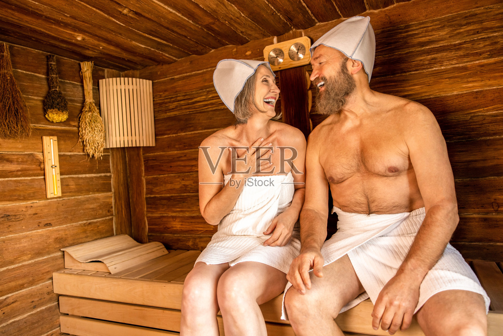 男人和女人坐在桑拿房里,看起来很兴奋照片摄影图片