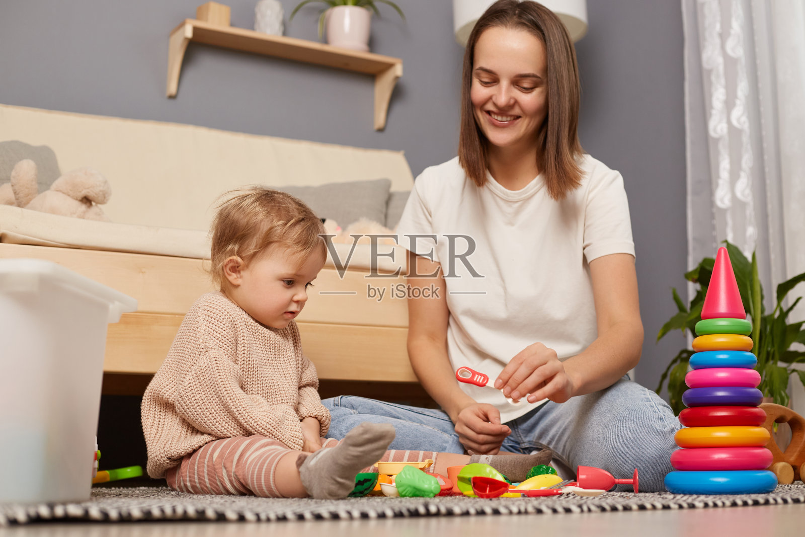 快乐的白人妈妈和小女儿在家里一起玩玩具,欣喜若狂的妈妈和小女孩坐在地板上一起学习。照片摄影图片