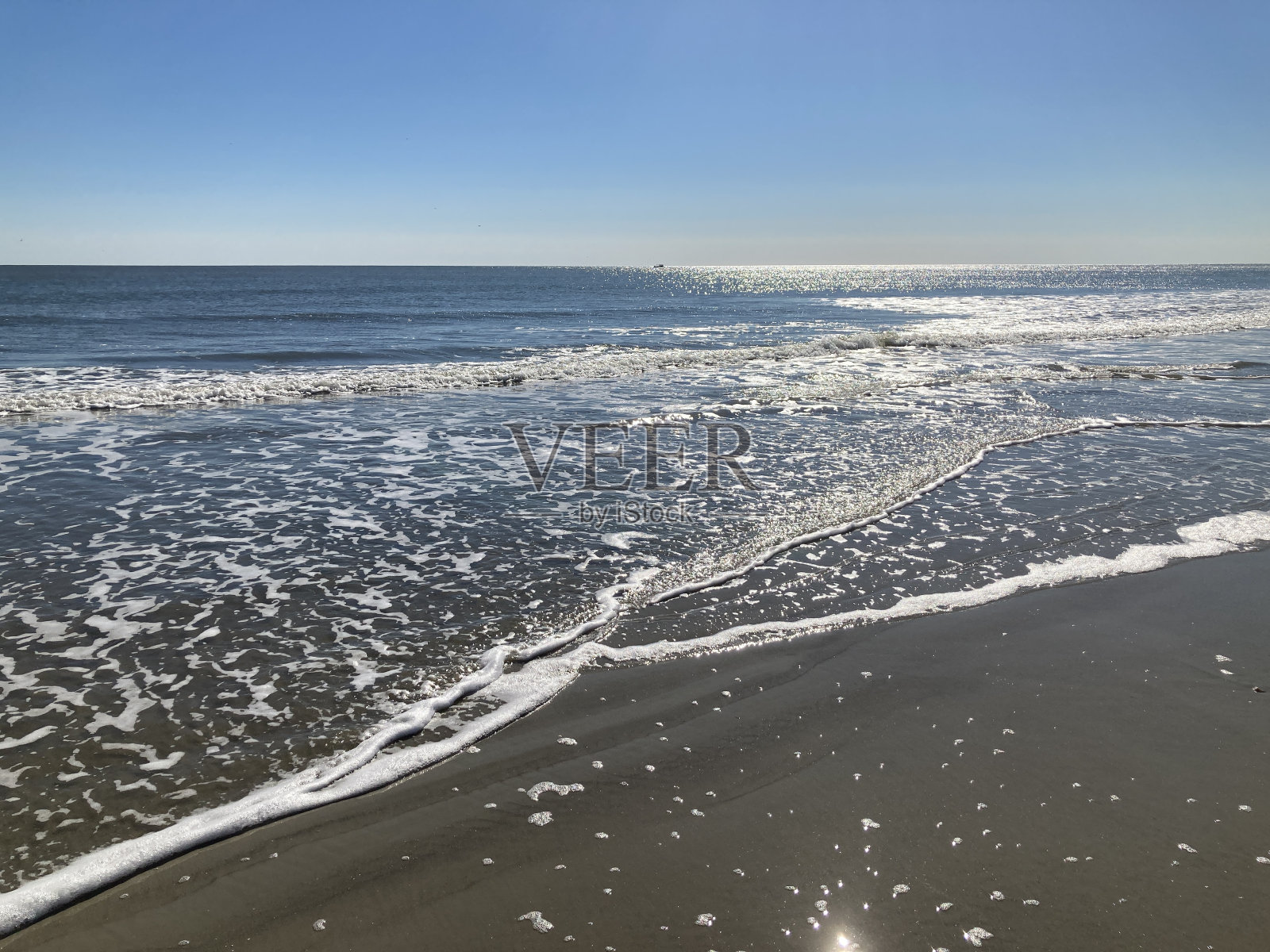 明亮的阳光照在水边的波浪上照片摄影图片