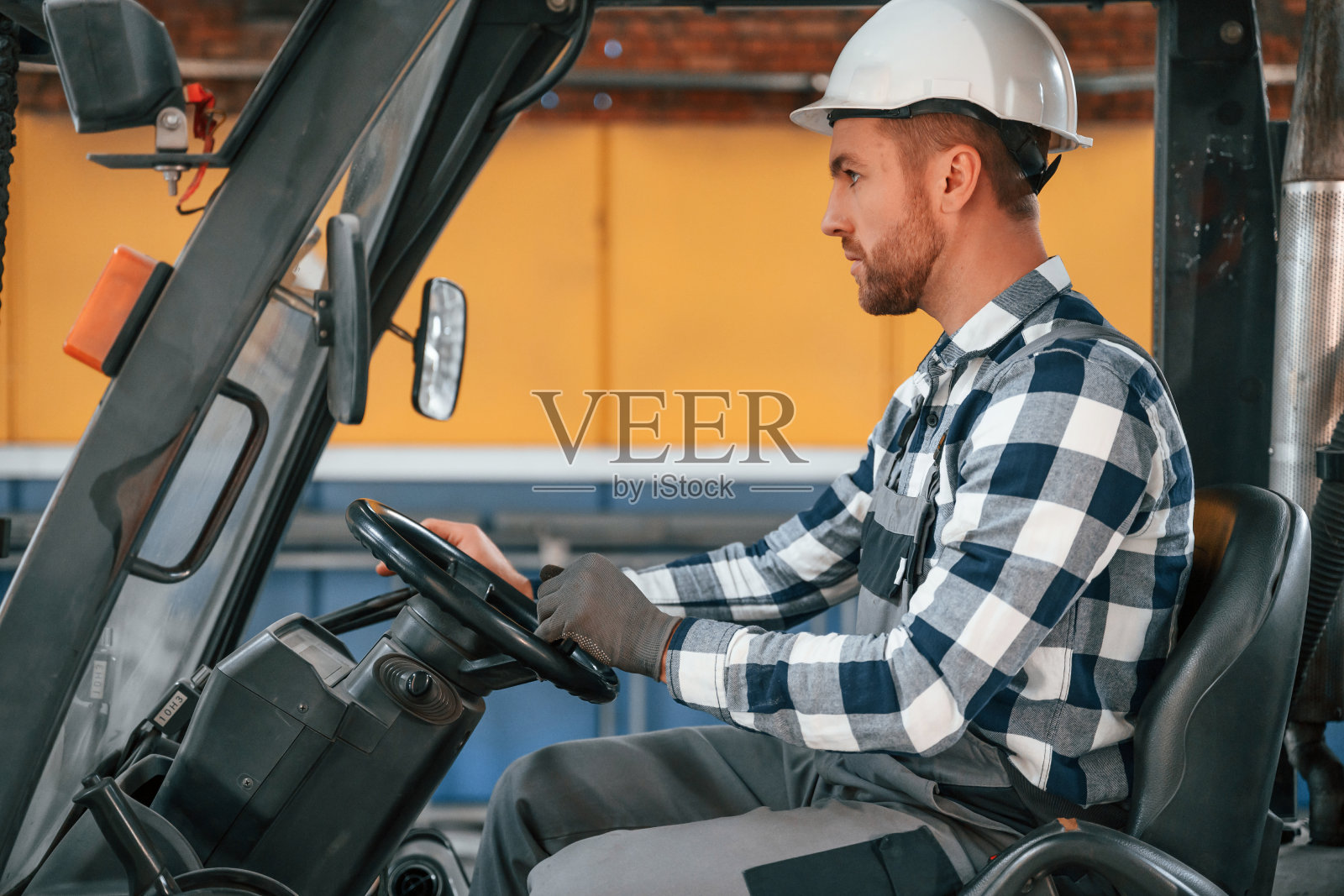 驾驶叉车。穿制服的工厂男工人在室内照片摄影图片