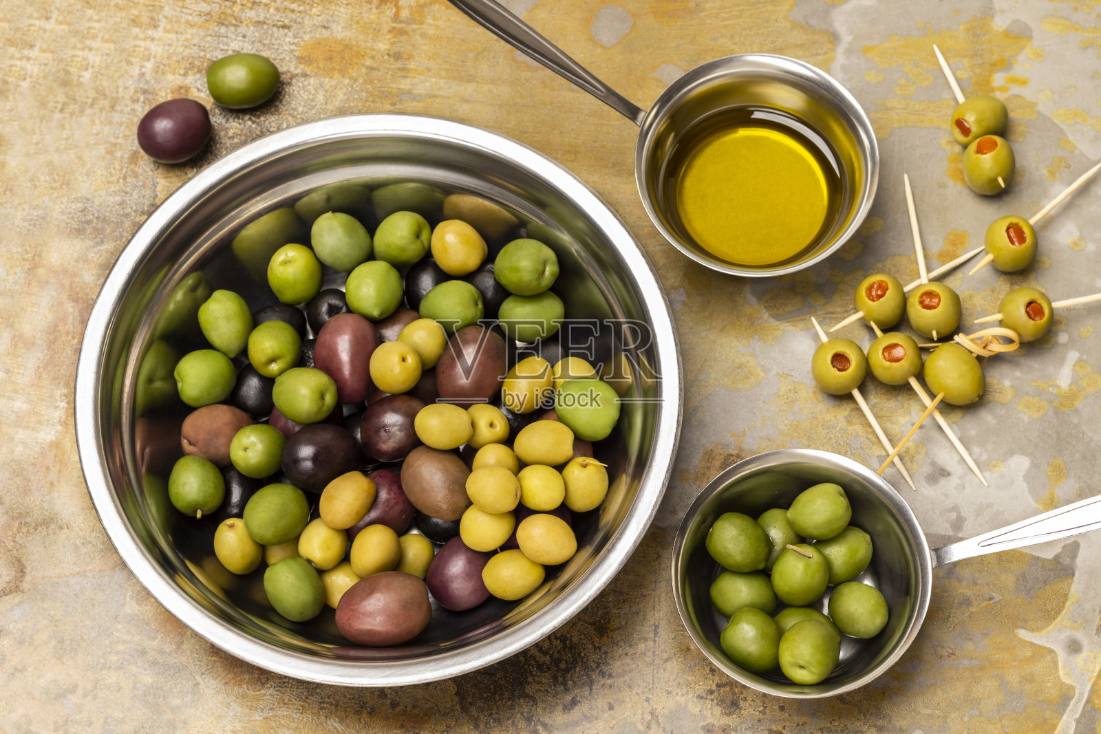 橄榄放在金属碗里。在碗里倒入橄榄油。橄榄串。照片摄影图片