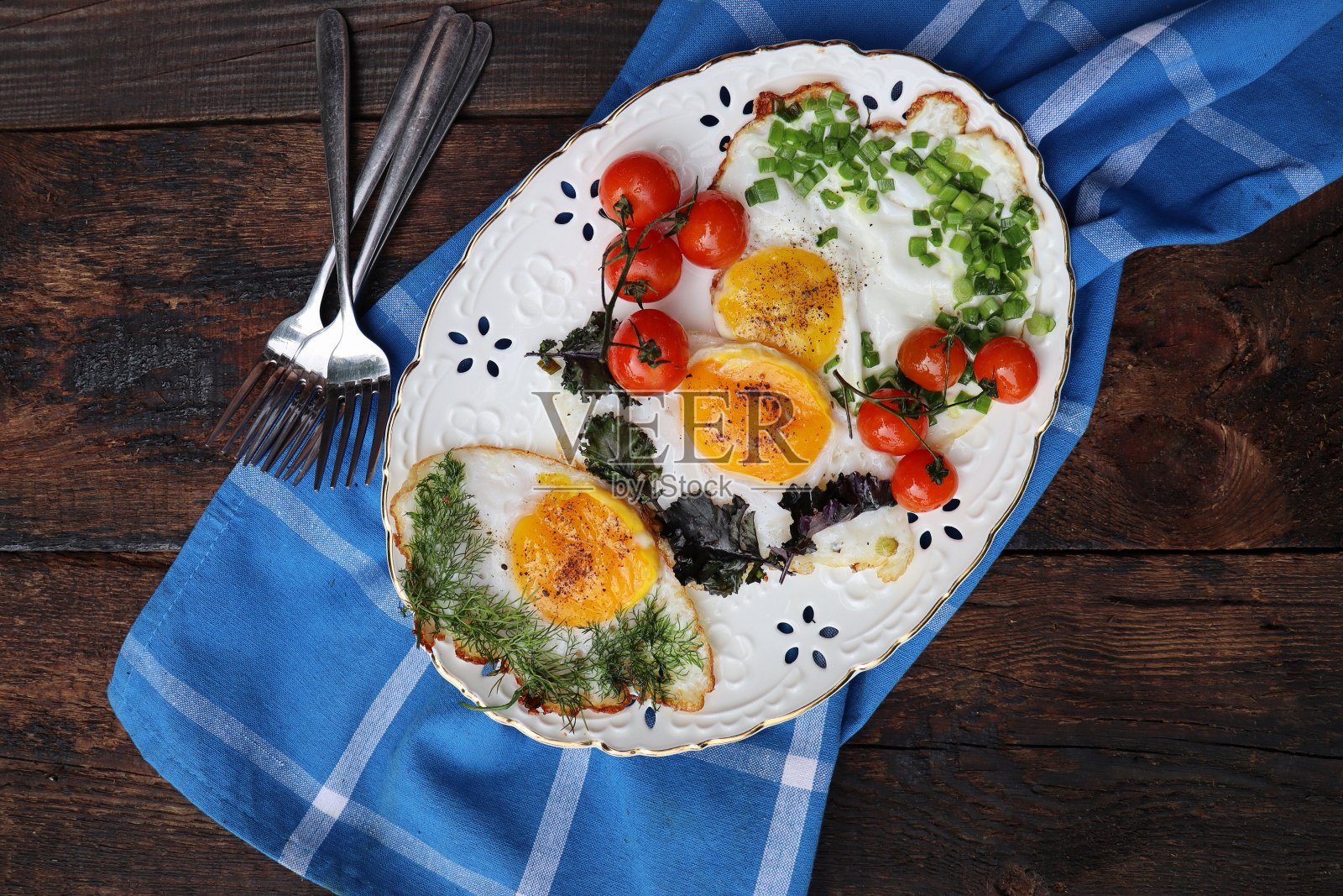 健康的早餐。新鲜做的美味的鸡蛋和蔬菜。香草、韭菜、洋葱、羽衣甘蓝、莳萝煎蛋照片摄影图片