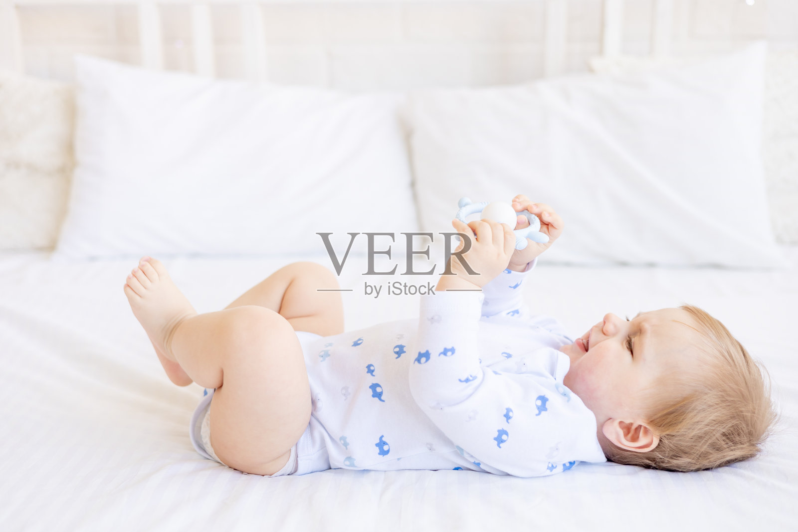 在儿童明亮的房间里,可爱的宝宝抱着一瓶吸吮的牛奶,仰卧在婴儿床上,婴儿食品概念照片摄影图片