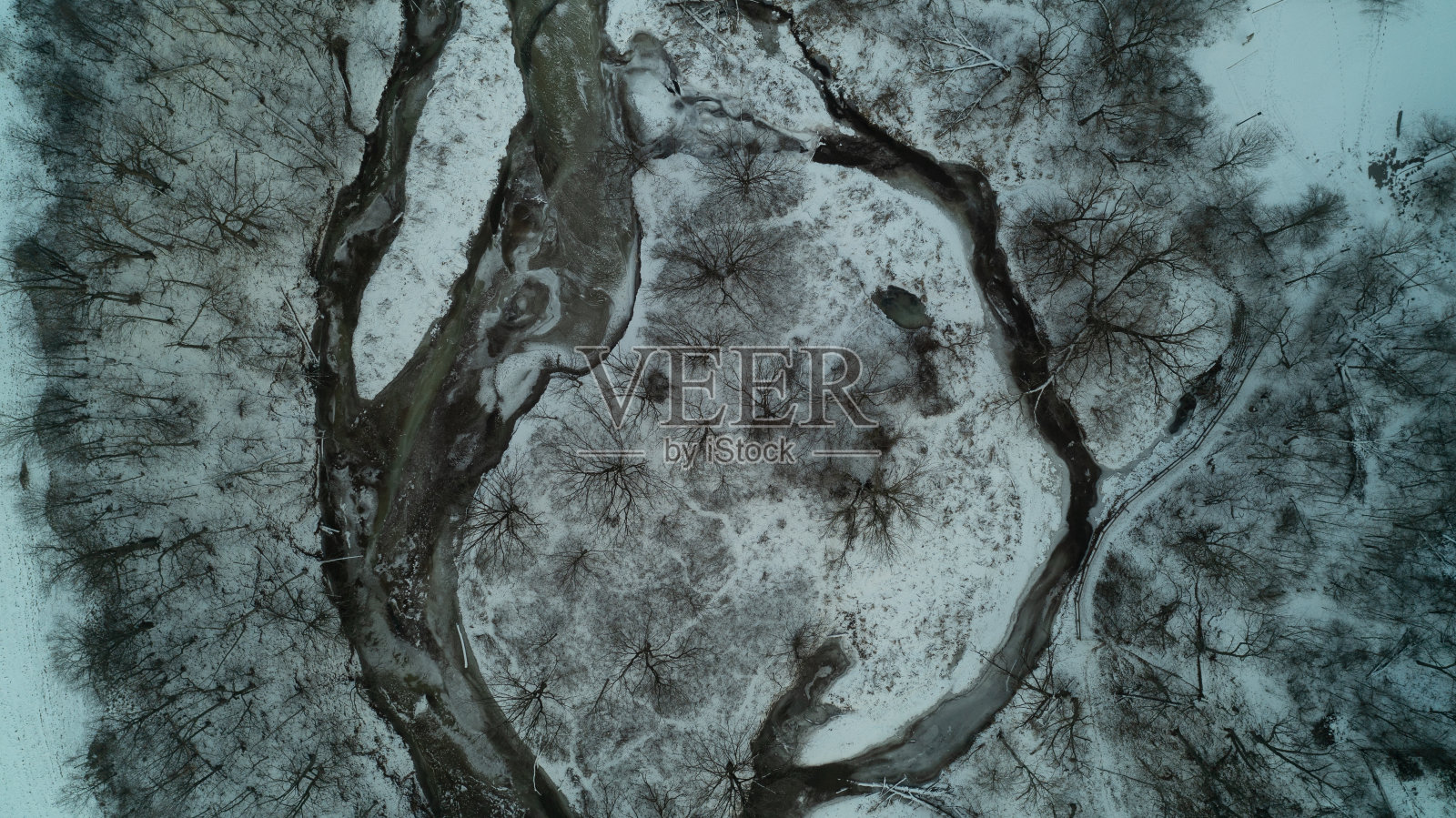 从高角度俯瞰森林里冬天被雪覆盖的小溪照片摄影图片