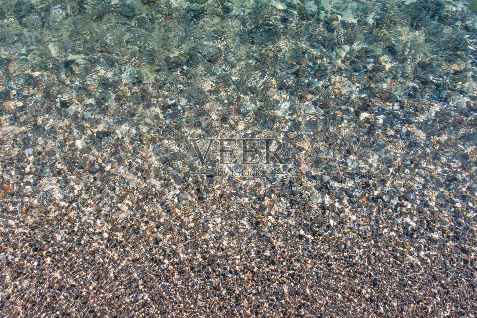 清澈的海水和反射阳光的彩色鹅卵石的美丽镜头照片摄影图片