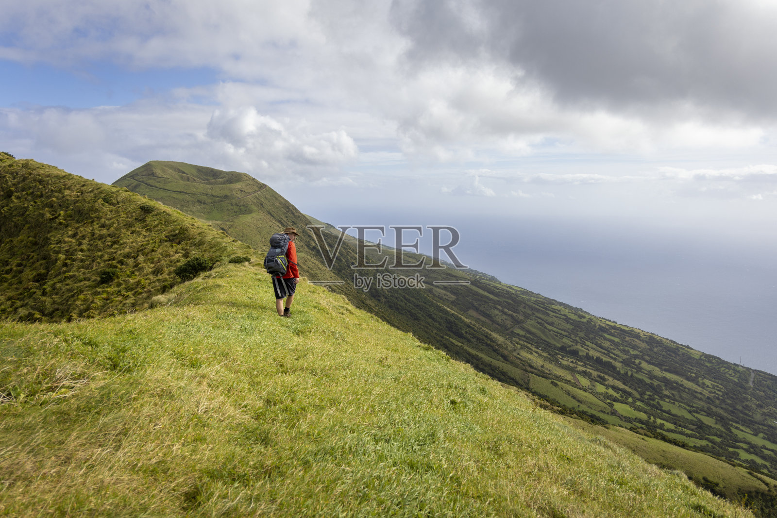 Person hiking along an old volcanic crater rim on São Jorge island in the Azores照片摄影图片
