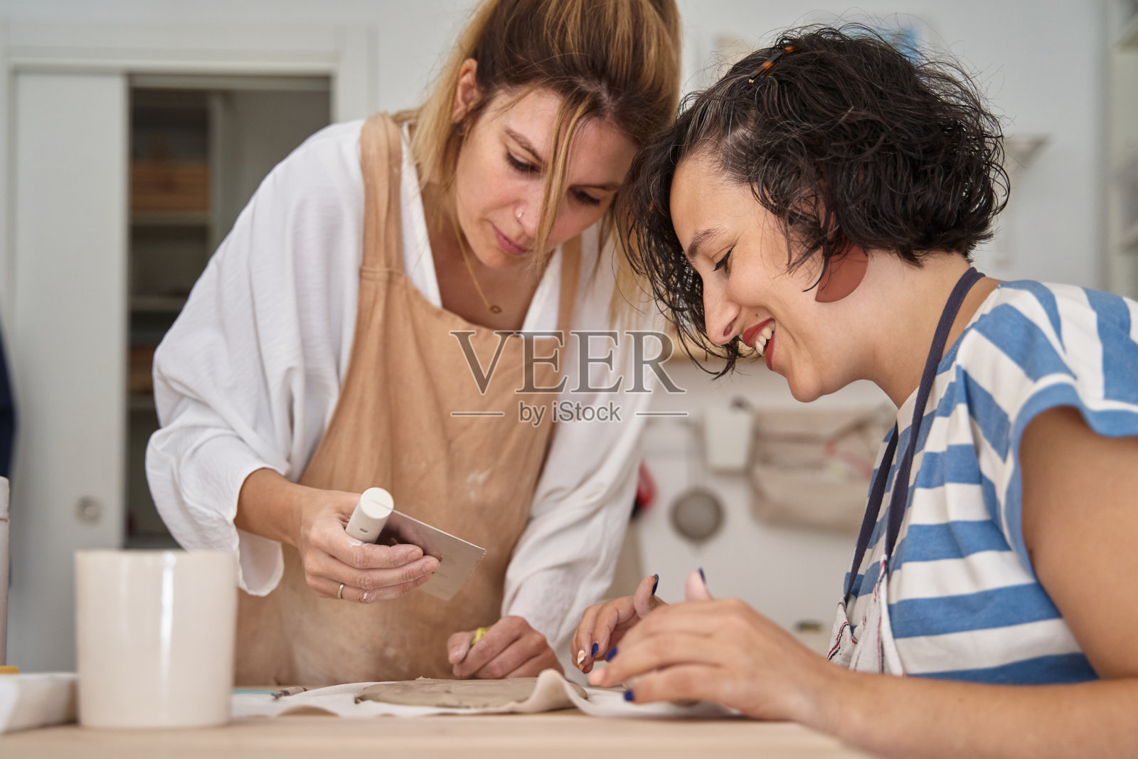 两个妇女在陶器作坊里摆弄粘土。照片摄影图片