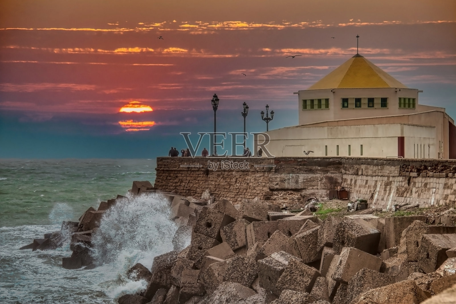 人们在西班牙加的斯的拉卡莱塔观看令人惊叹的日落照片摄影图片