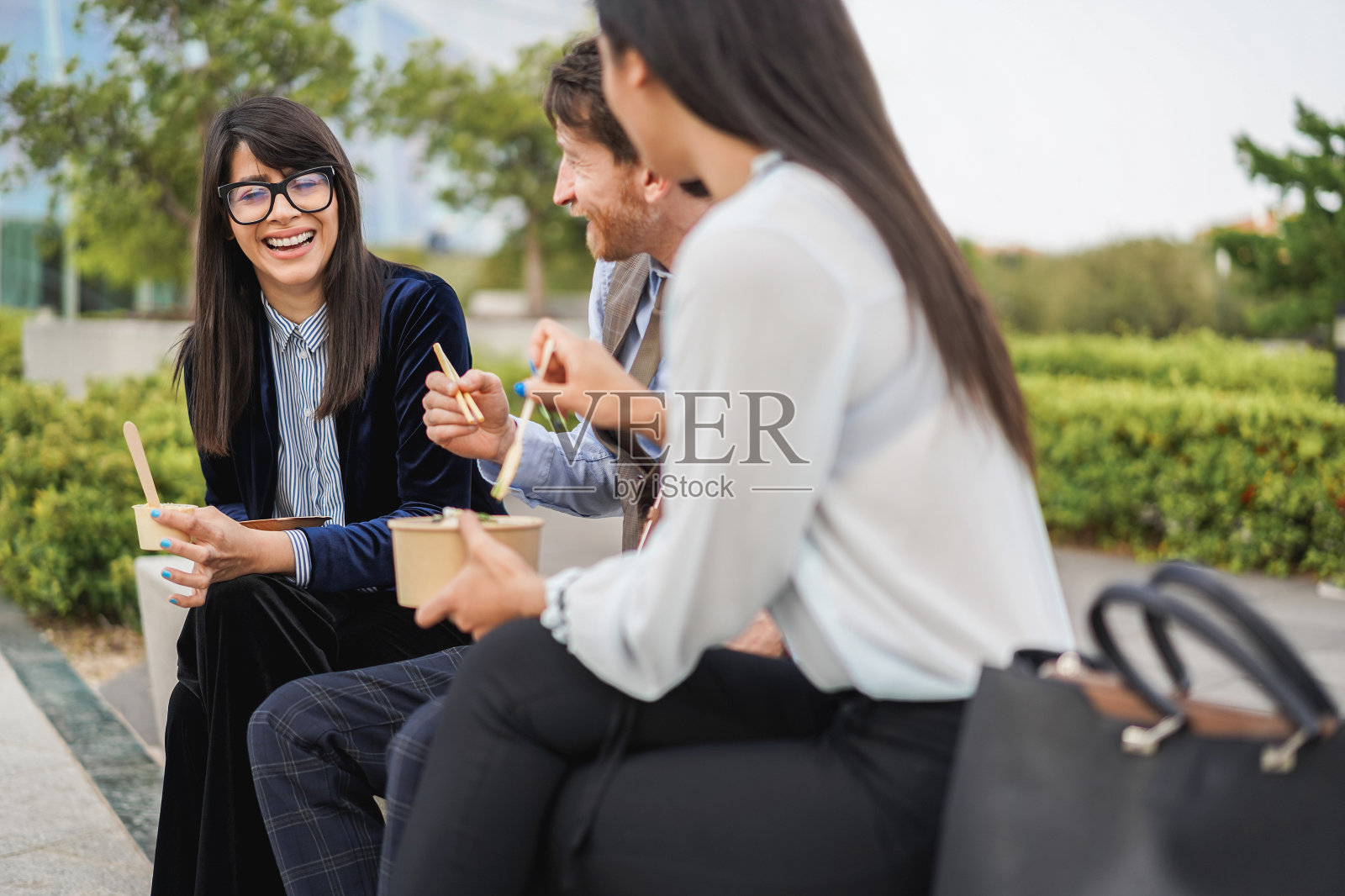 商务人士在办公大楼外吃午饭-注意中间男人的脸照片摄影图片