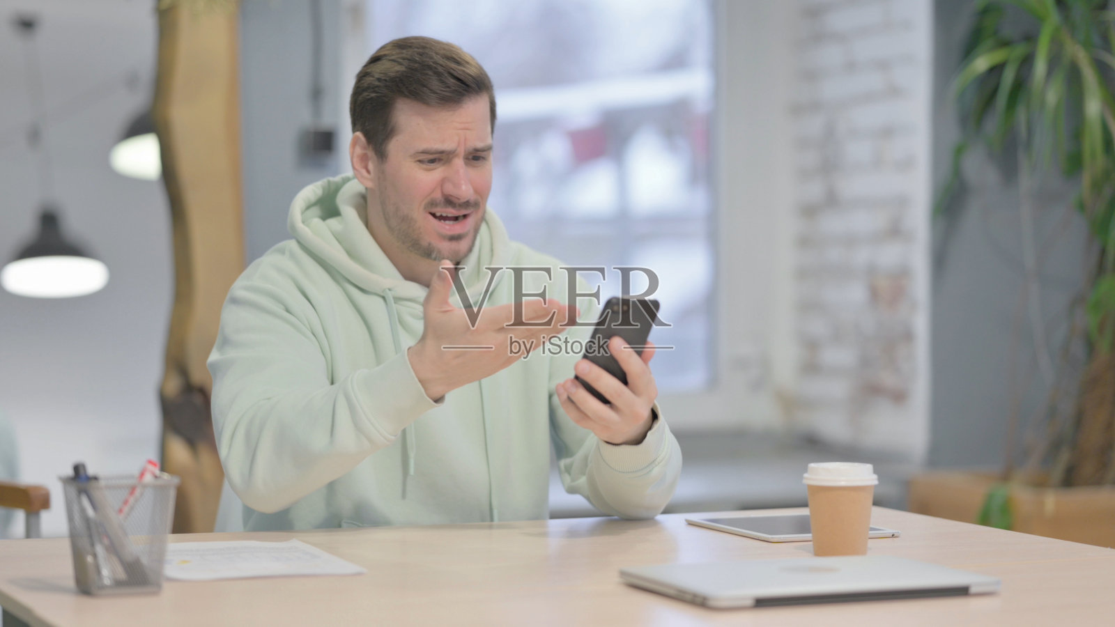 对智能手机损失做出反应的沮丧的年轻人照片摄影图片