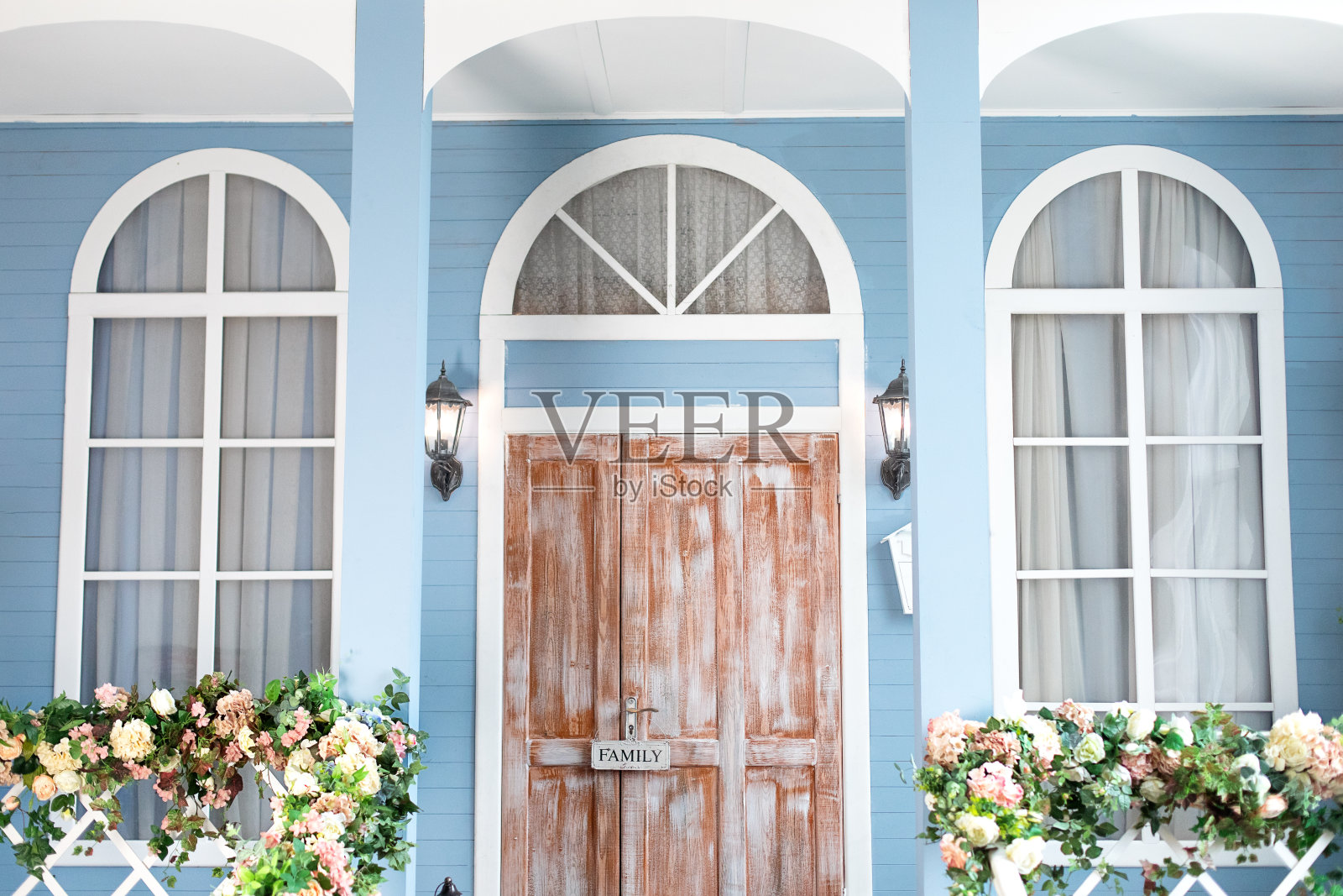 家中、室外都有拱形窗户。木门廊的房子,不同的花。避暑别墅的露台。春天设计家与盛开的鲜花。为复活节装饰的房子入口楼梯。照片摄影图片