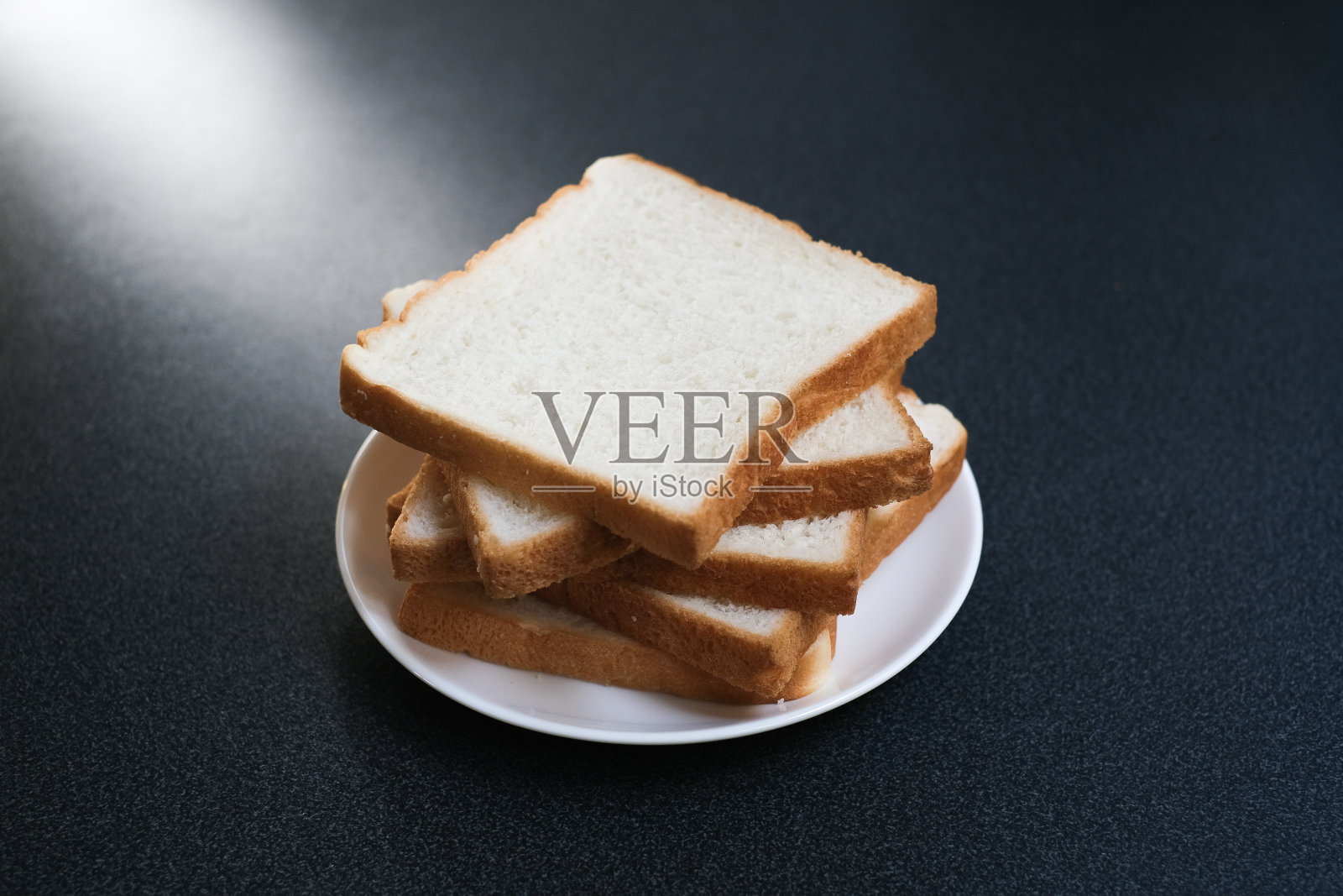 白盘子里的切片面包,早上自制的早餐面包。照片摄影图片