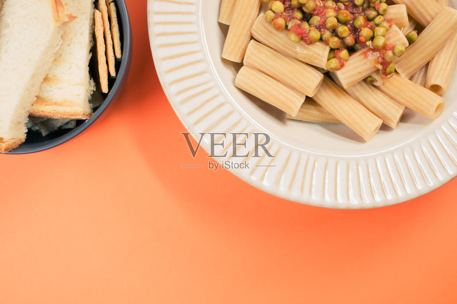 俯视图的通心粉与绿色豌豆和面包片孤立的橙色背景照片摄影图片