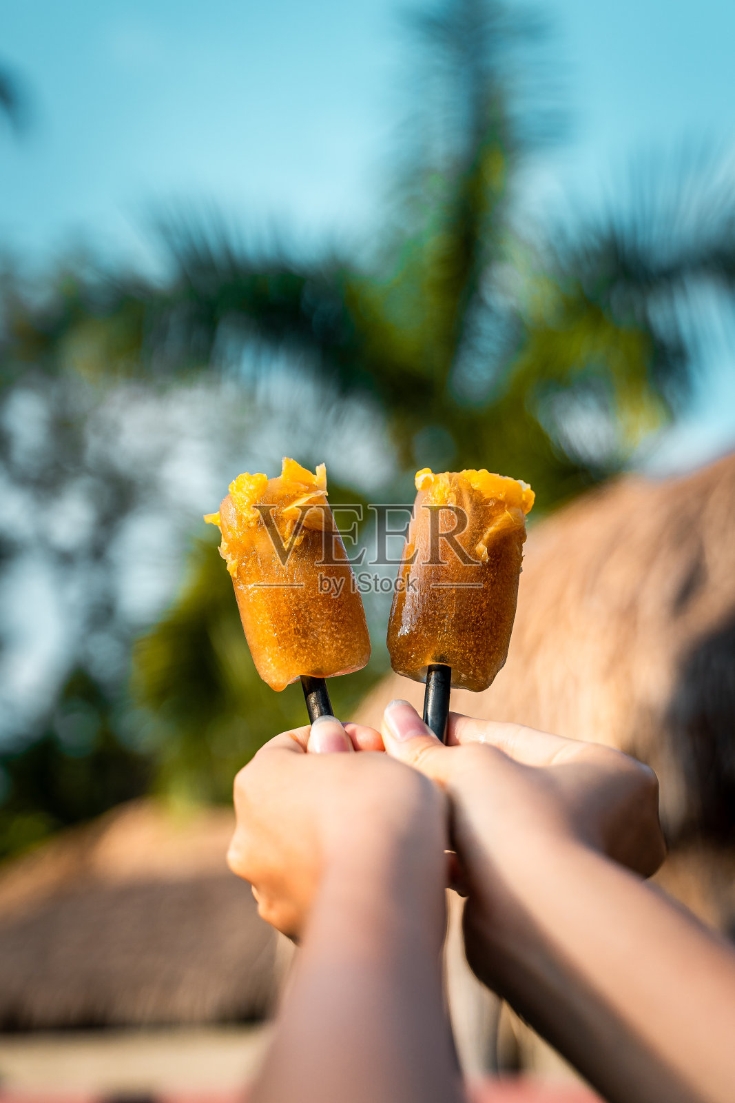 朋友们举着自制的橙色冰淇淋的垂直镜头照片摄影图片